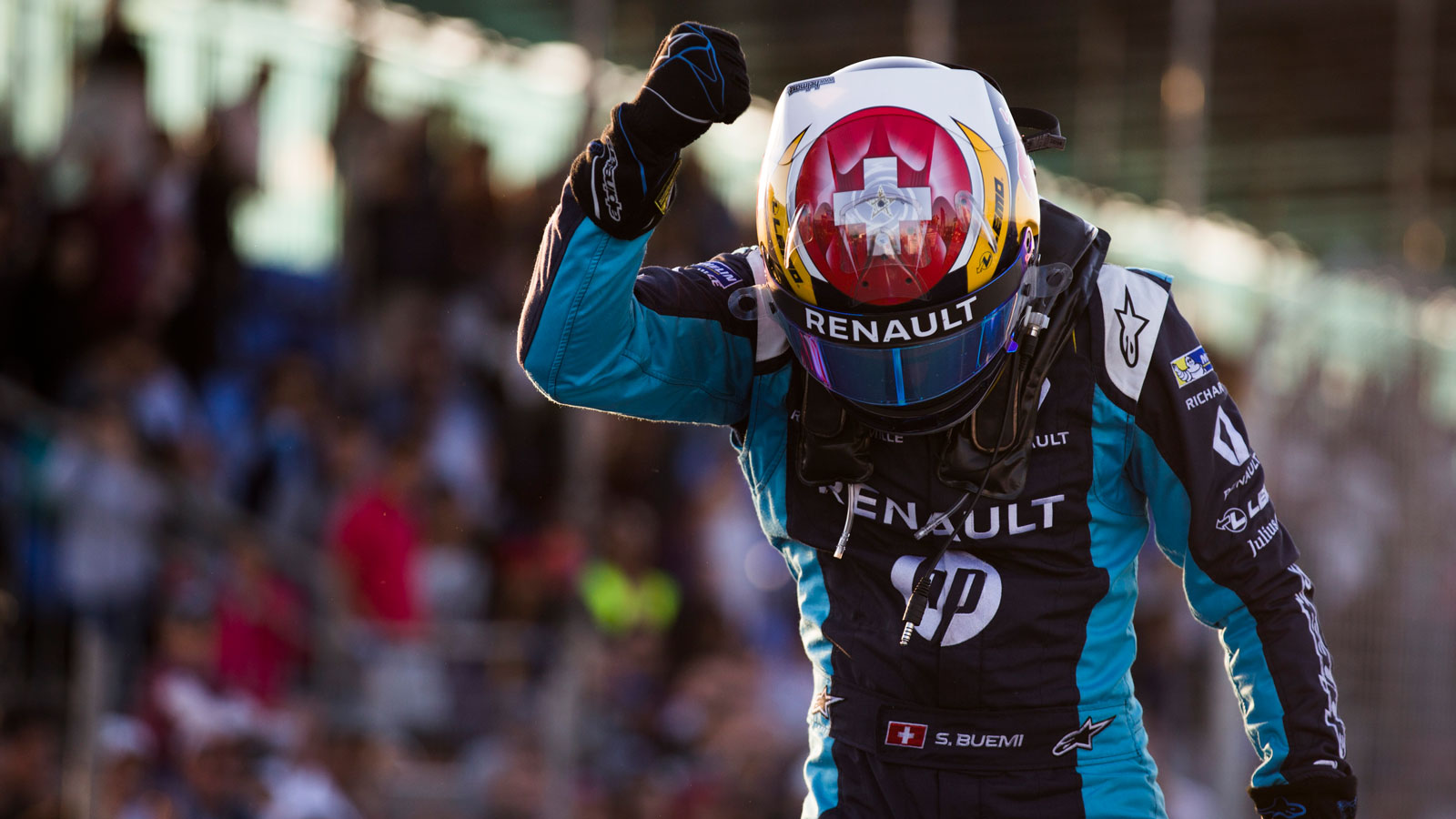 A photo of Sébastien Buemi pointing to his helmet after winning a race. 