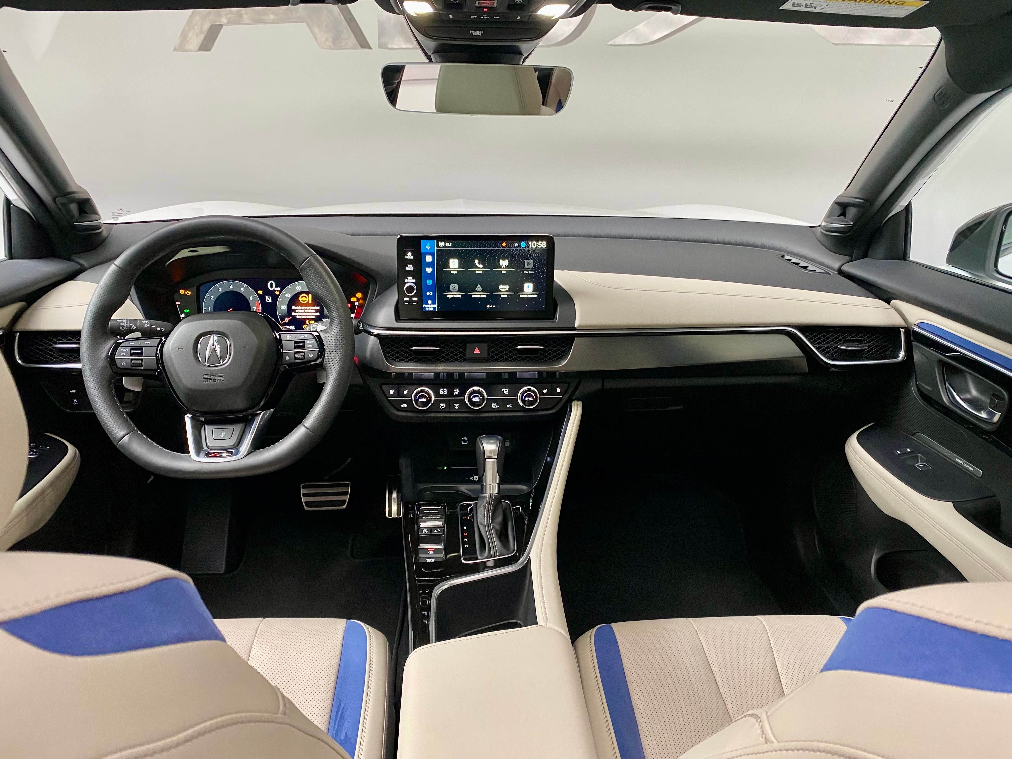 A photo of the ADX's dashboard from the back seat showing white seats with bright blue accents