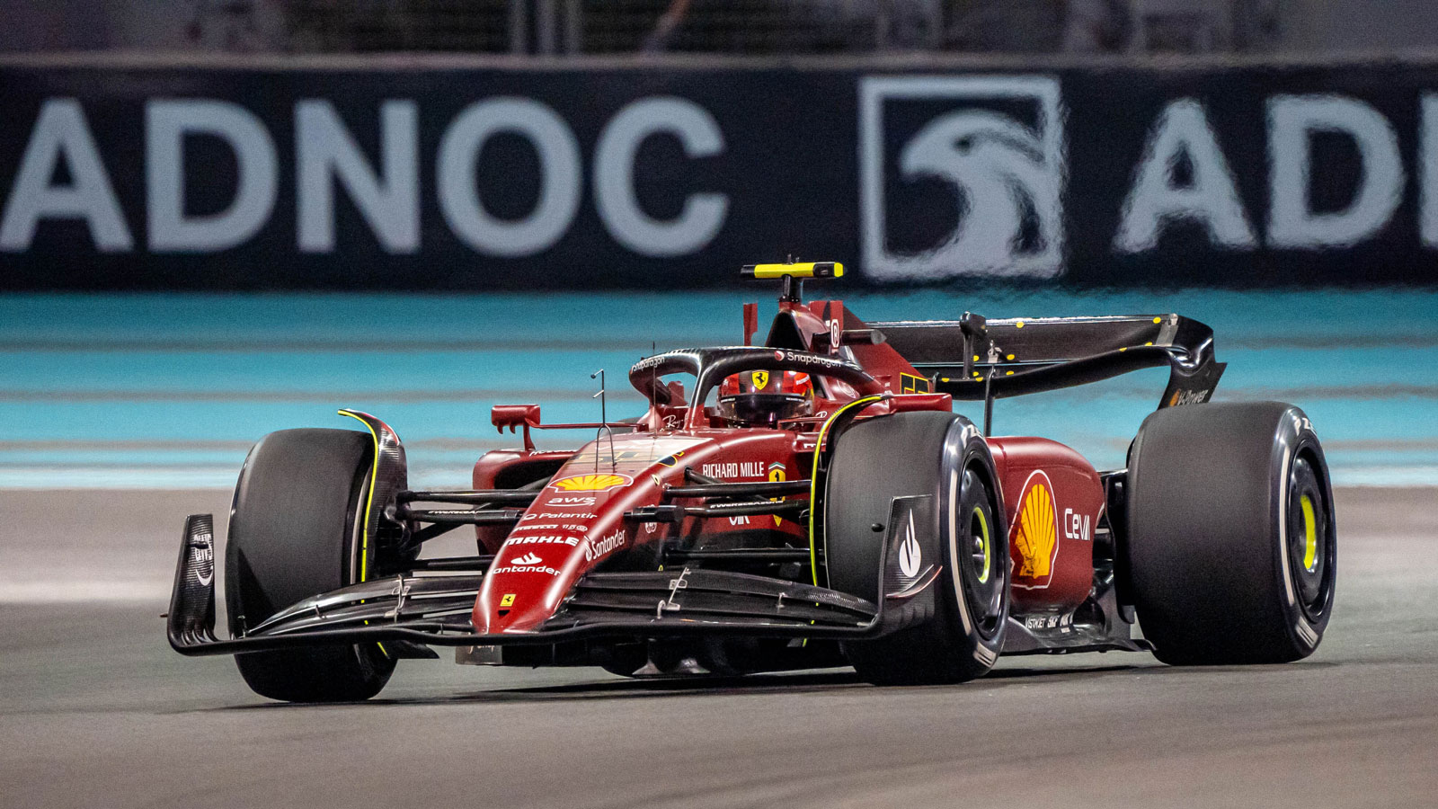 A photo of a red Ferrari f1 car racing in Abu Dhabi. 