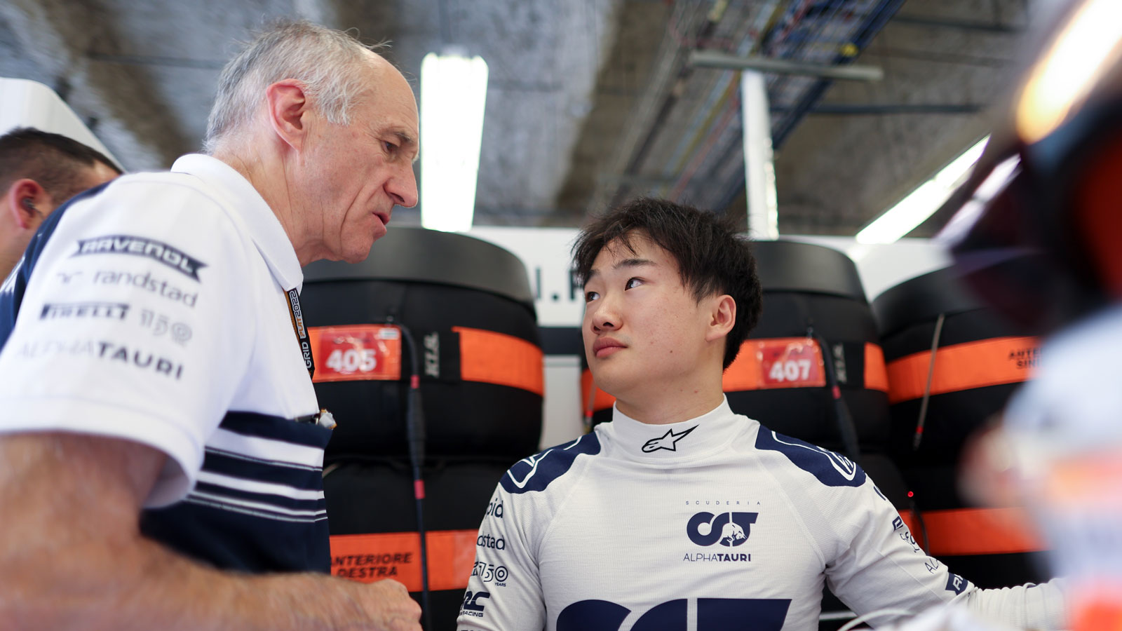 A photo of Yuki Tsunoda and Franz Tost talking in the F1 garage. 