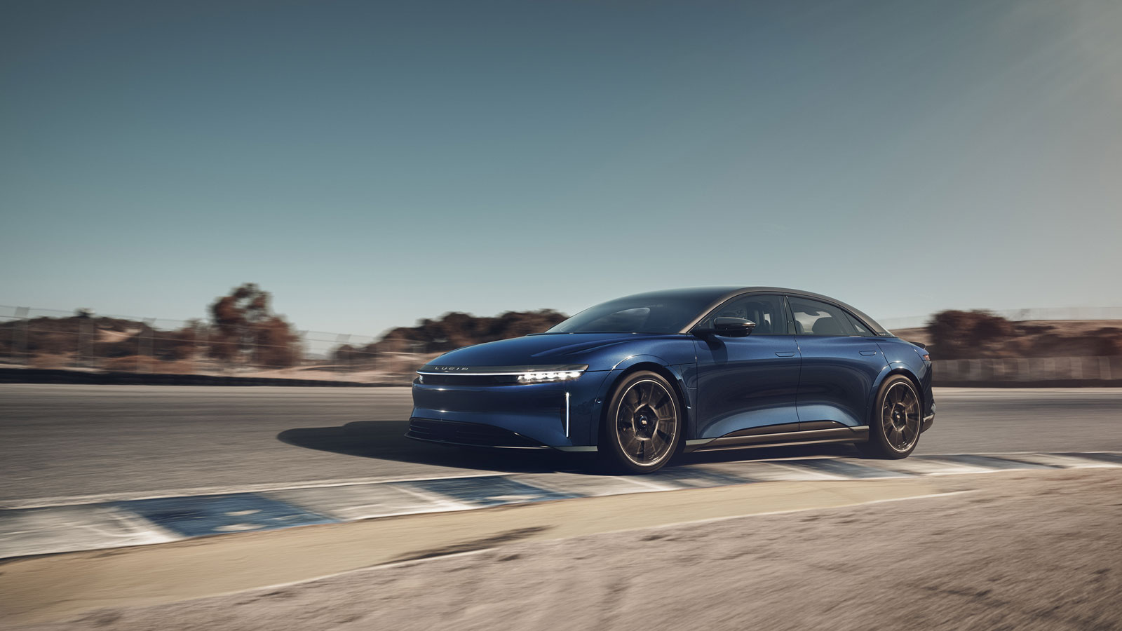 A photo of a blue Lucid Air Sapphire EV driving on a race track. 