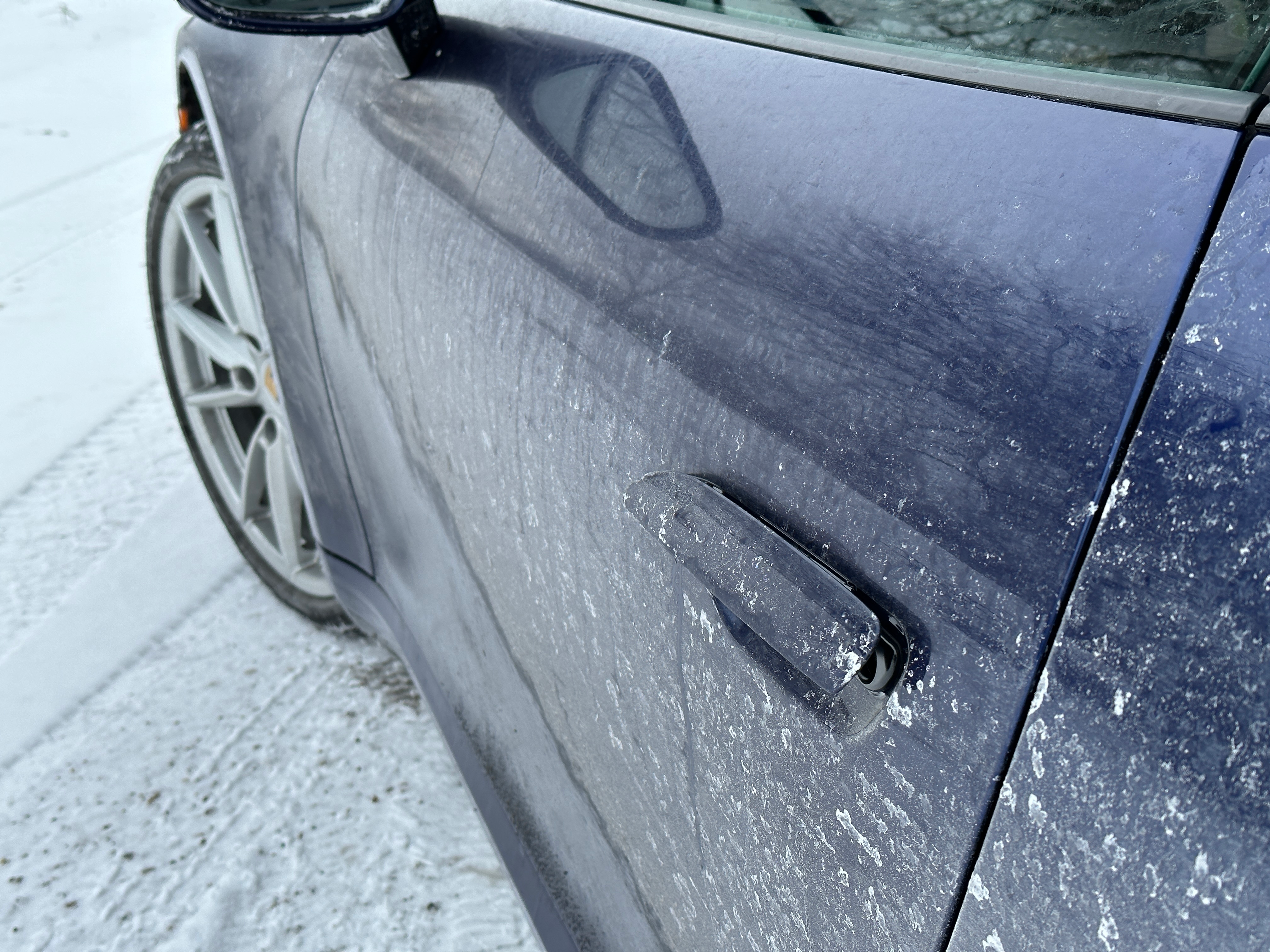 a blue 2023 porsche 911 carrera on a snow-covered road in michigan