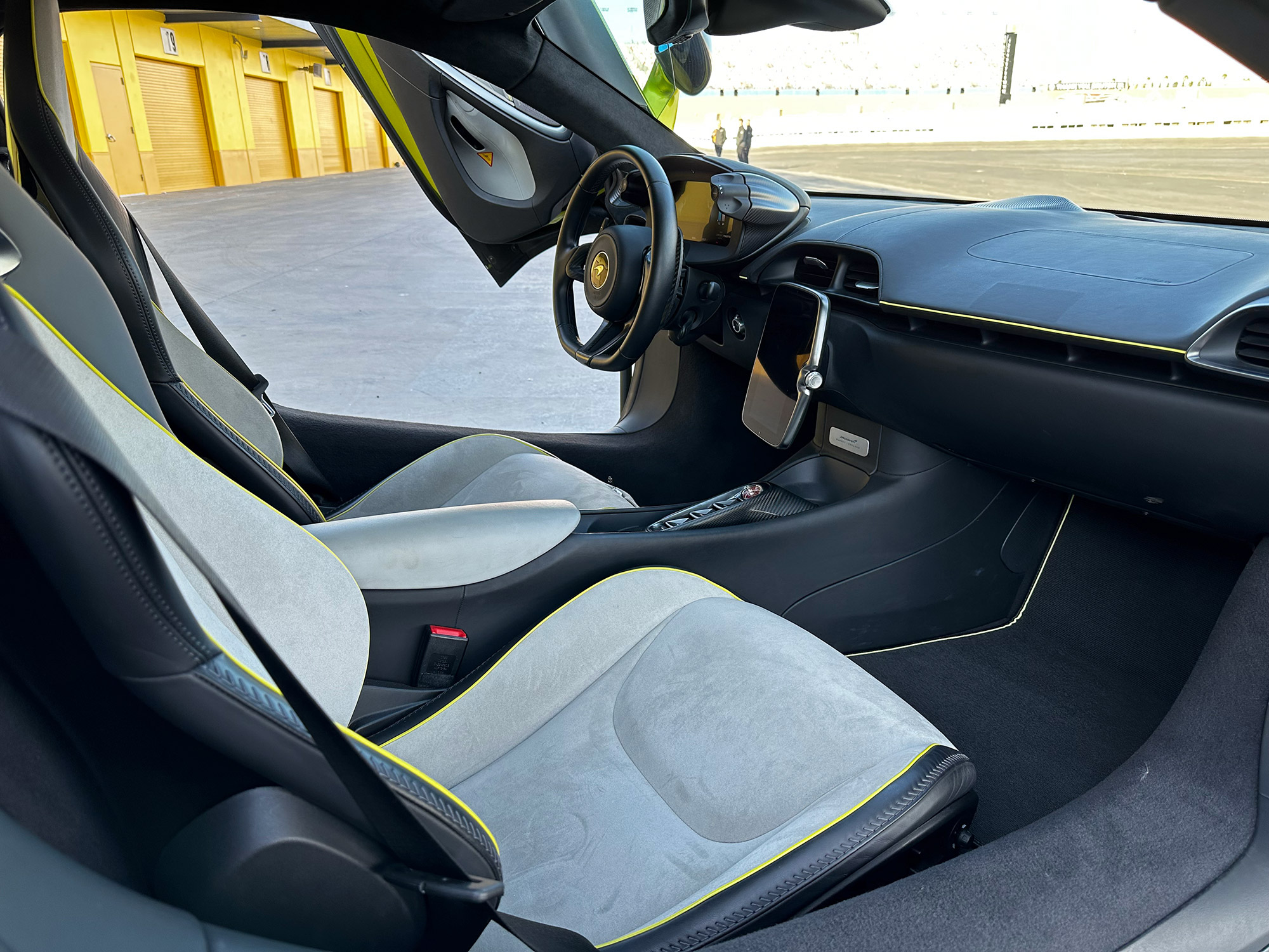 View of the passenger side of the interior of a Flux Green McLaren Artura with the door open.