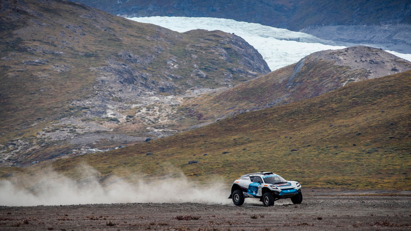 An Extreme E off-roader races across a glacier. 