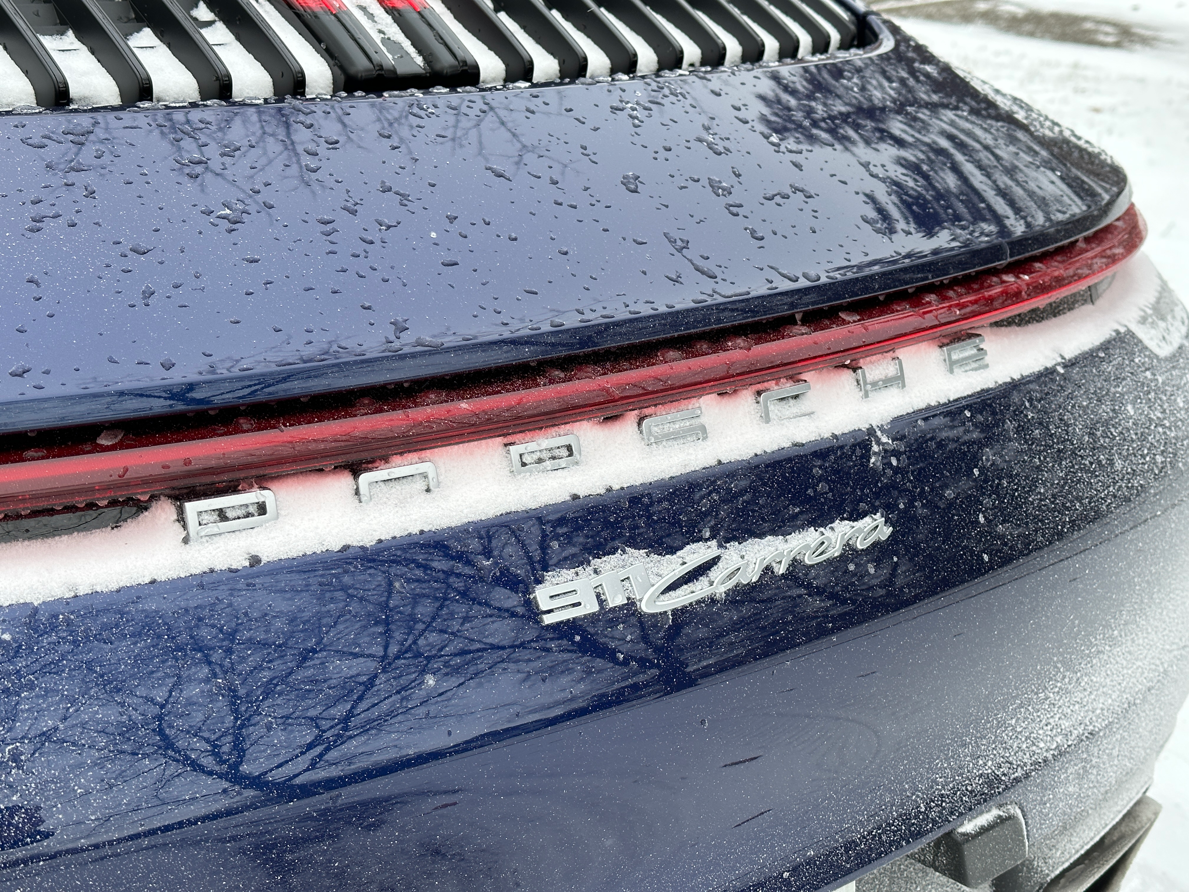 a blue 2023 porsche 911 carrera on a snow-covered road in michigan