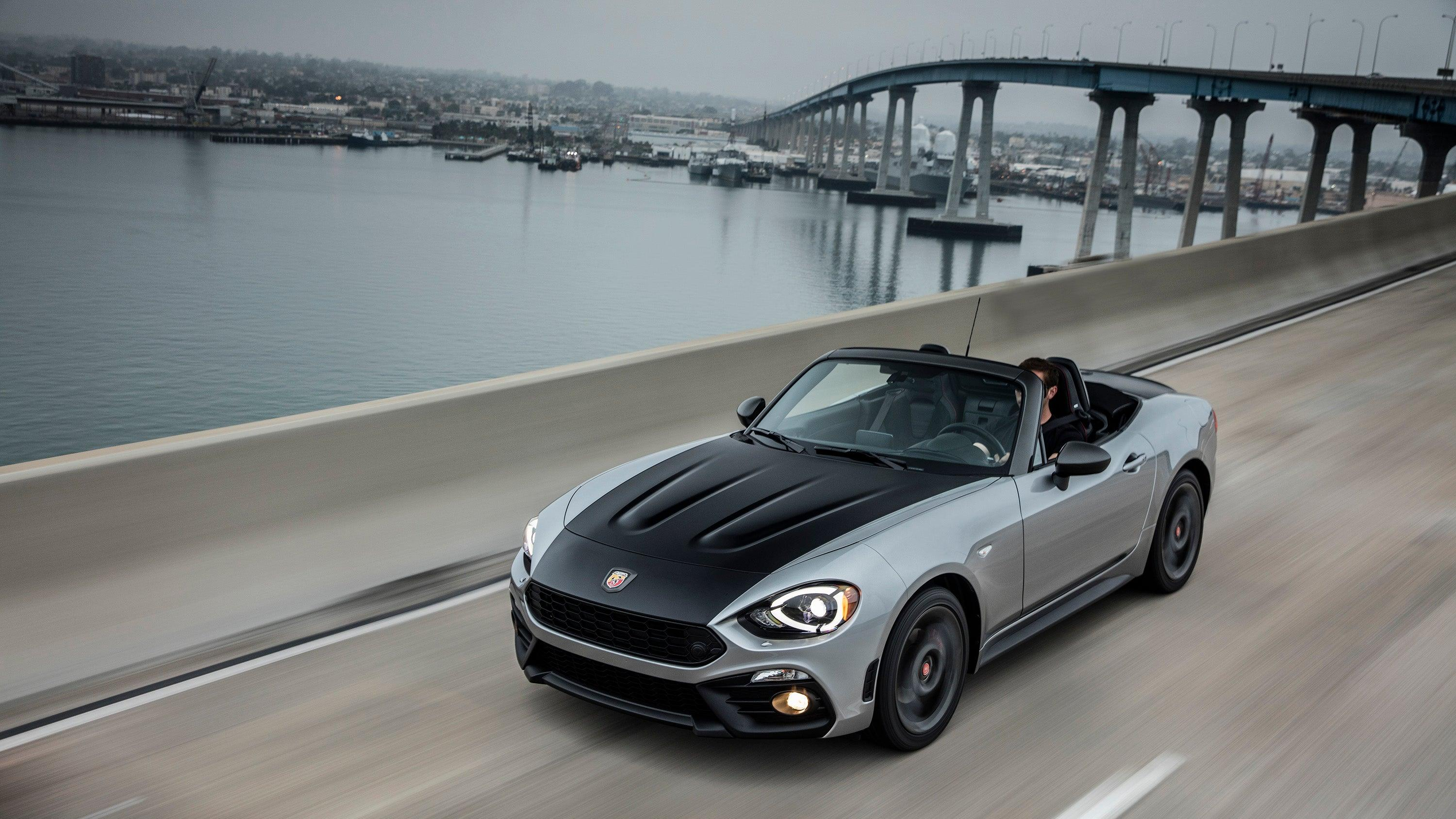 A silver 2020 Fiat 124 Spider Abarth driving across a bridge over water