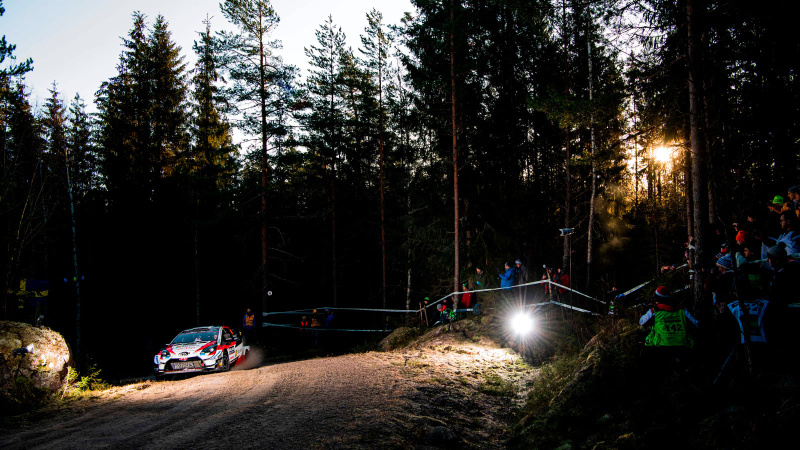 A photo of a car completing the Rally Sweden course as sun sets. 