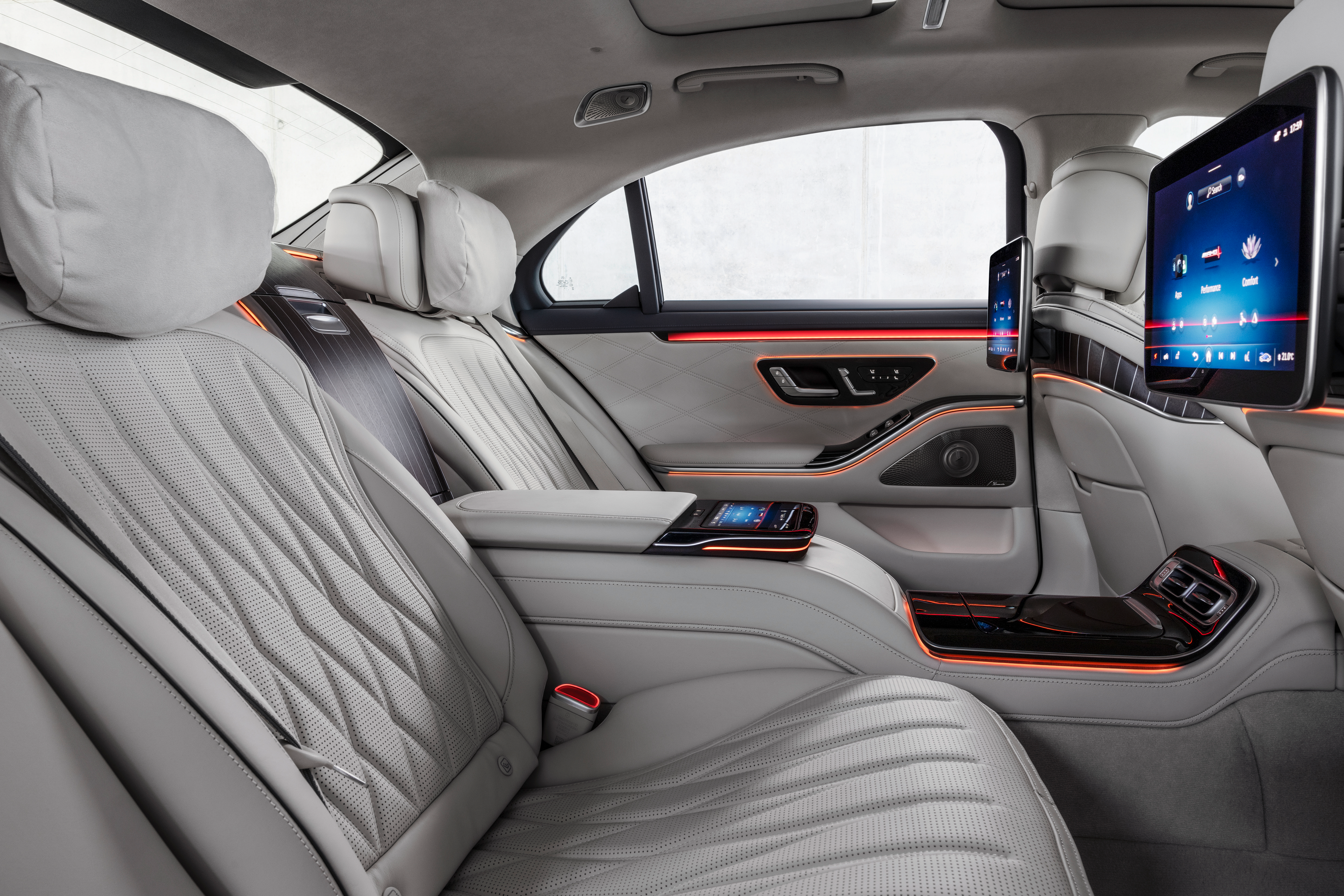 the interior of the 2023 mercedes-amg s 63 e performance sedan, seen from the right-rear seat. the upholstery is dove grey and orange accent lighting emanates from the doors and center console.