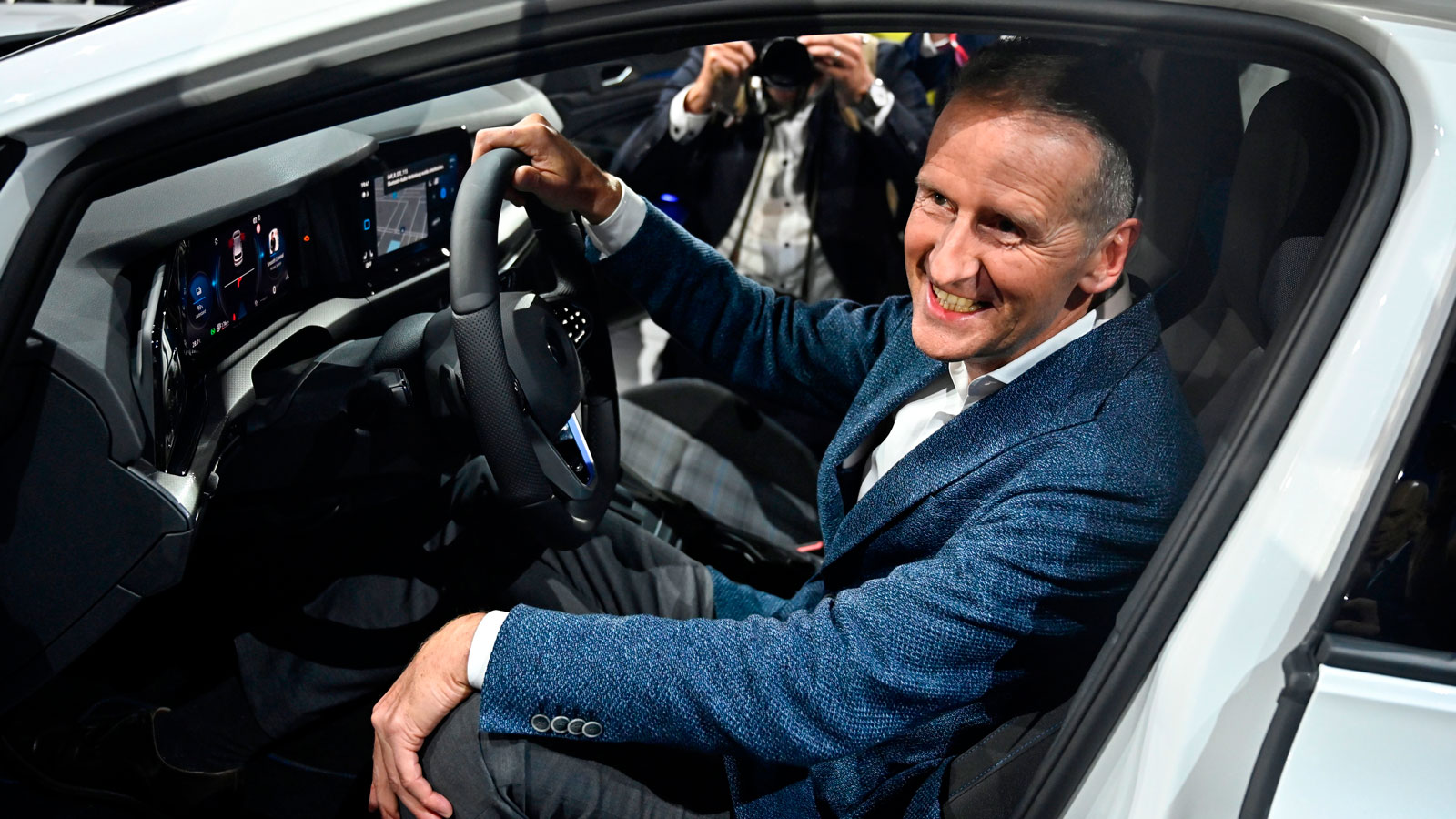 A photo of Herbert Diess sat at the wheel of a car. 