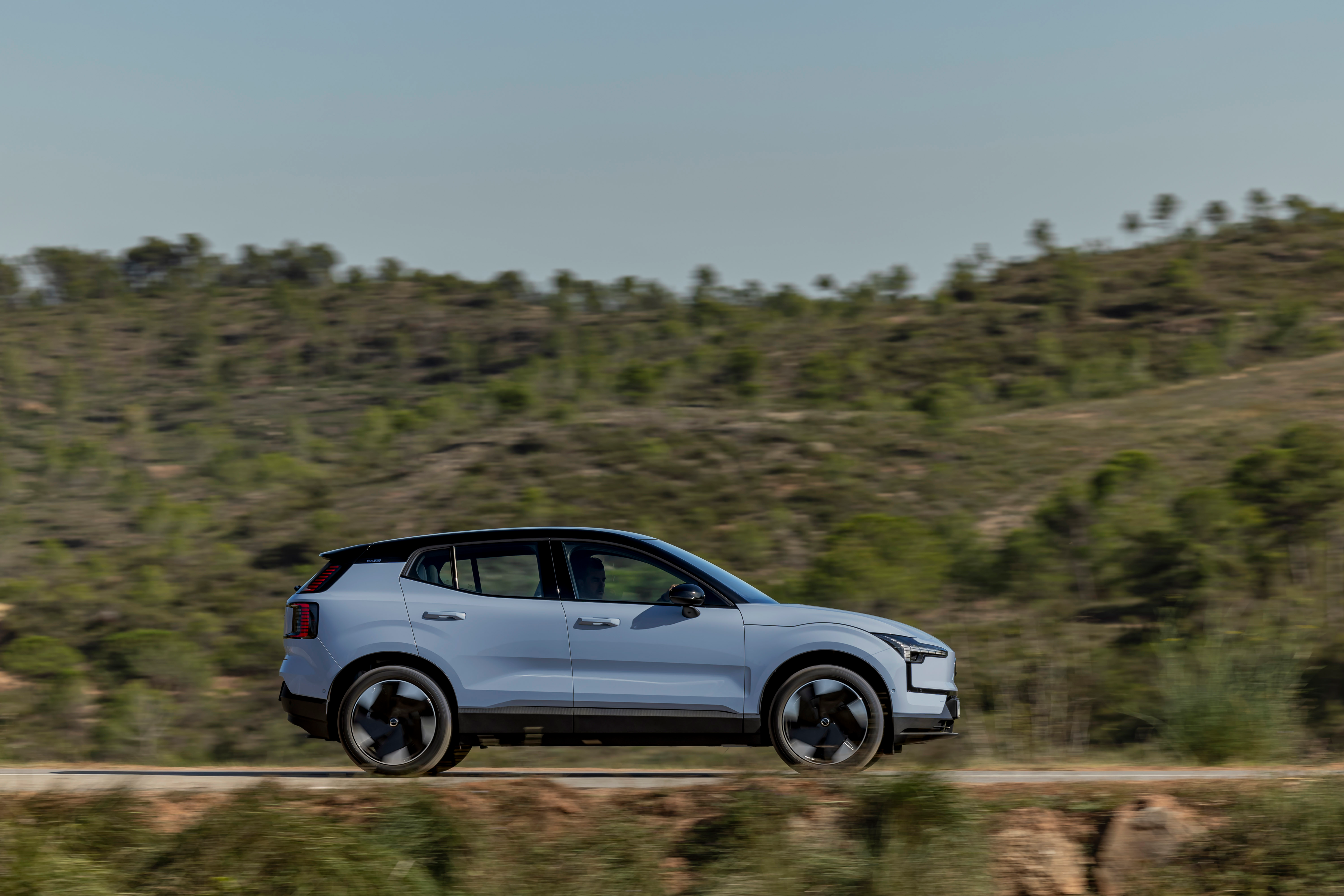 2024 Volvo EX30 speeding down the road with green hills in the background