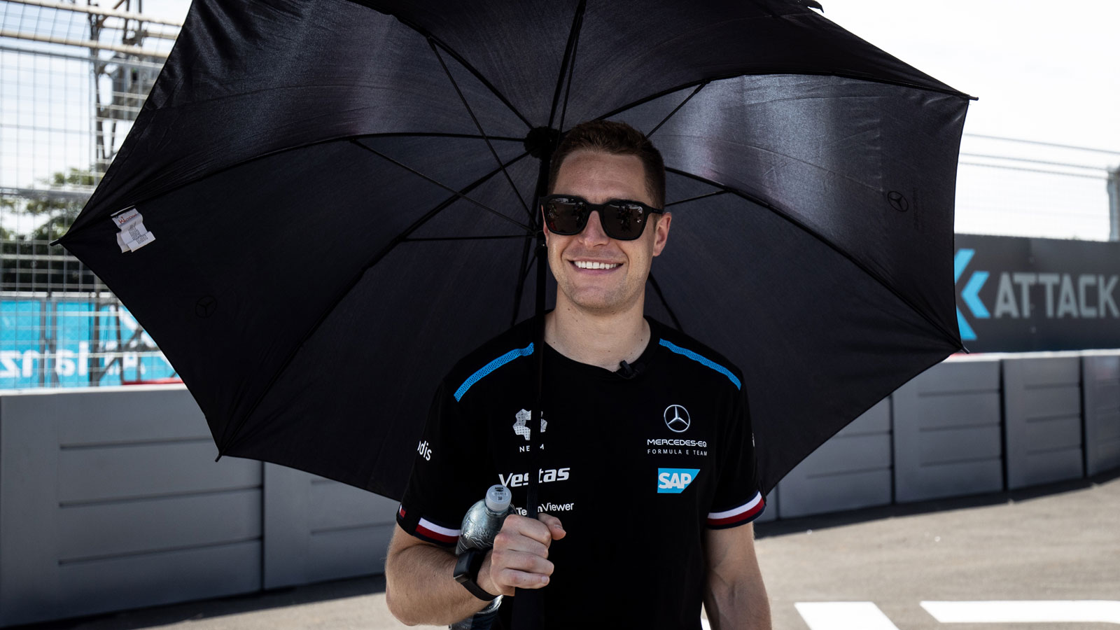 A photo of Mercedes driver Stoffel Vandoorne holding a black umbrella. 