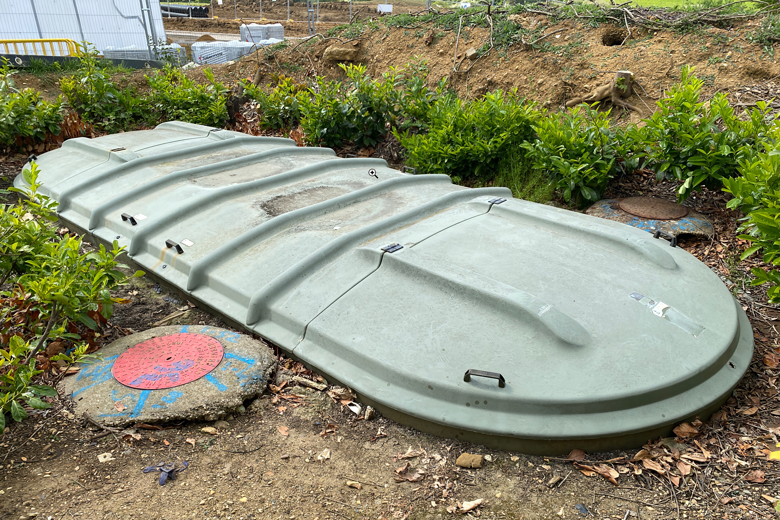 The dark green septic tank sunken into the ground.