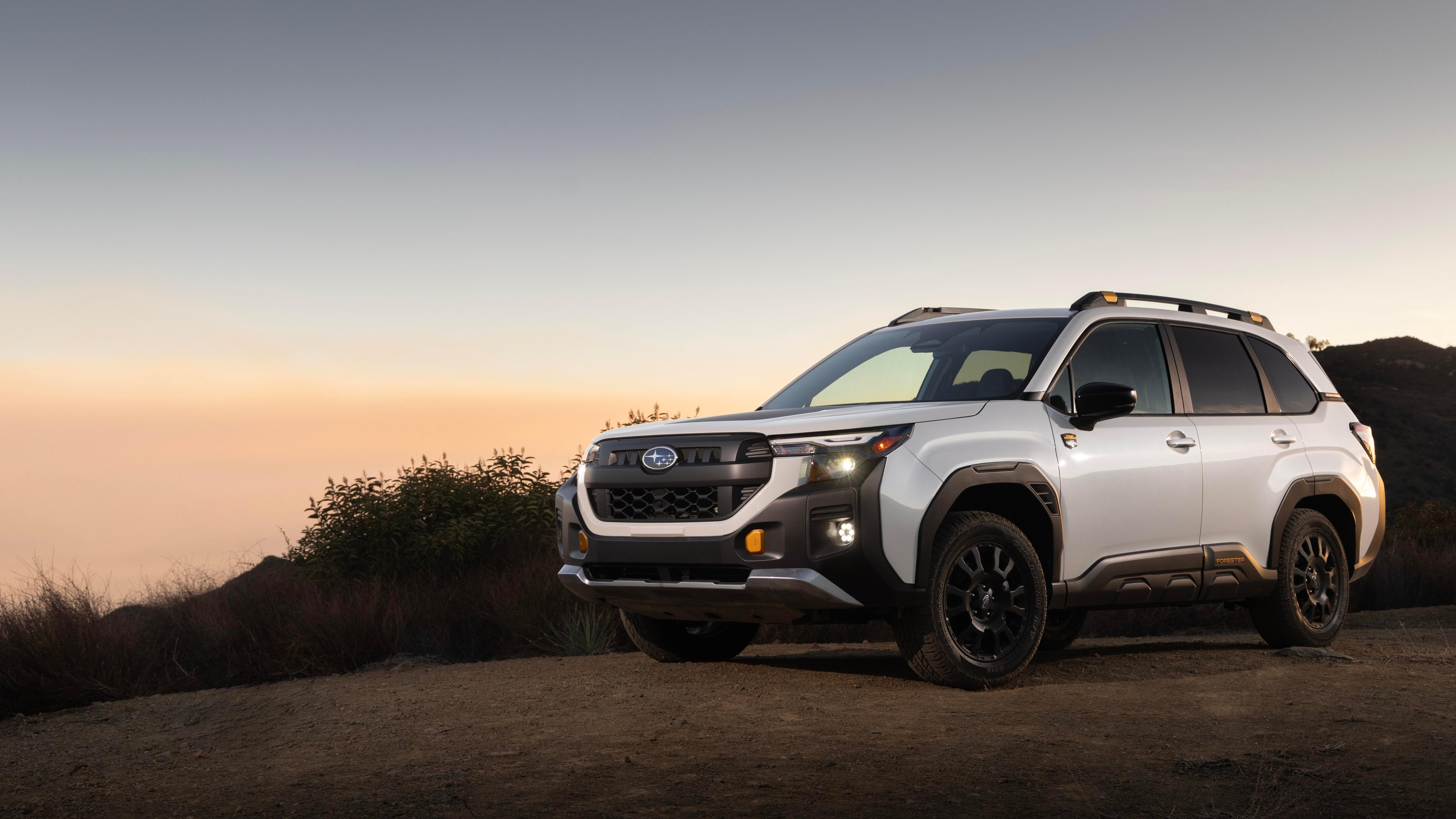 A front three-quarters shot of a white forester wilderness parked in front of a sunset