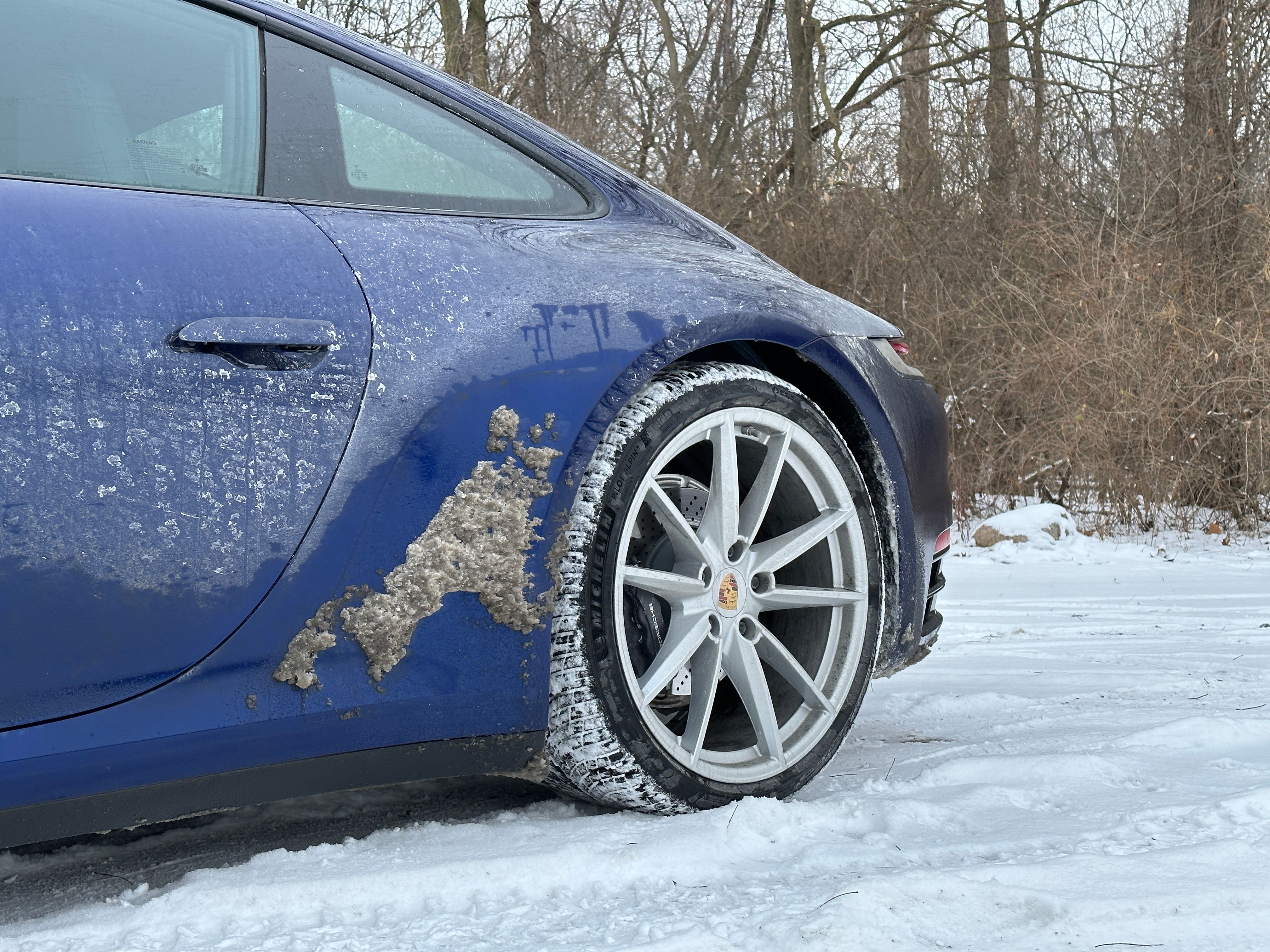 a blue 2023 porsche 911 carrera on a snow-covered road in michigan