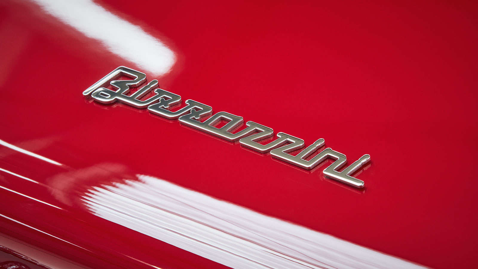 A close up photo of the chrome Bizzarrini logo on the red bodywork. 