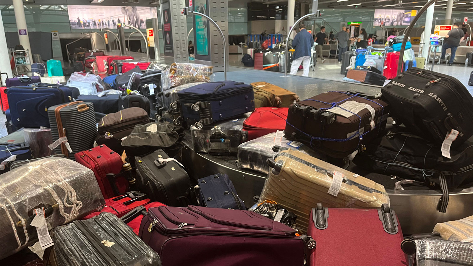 A photo of suitcases piled up on a baggage carousel at Heathrow Airport. 