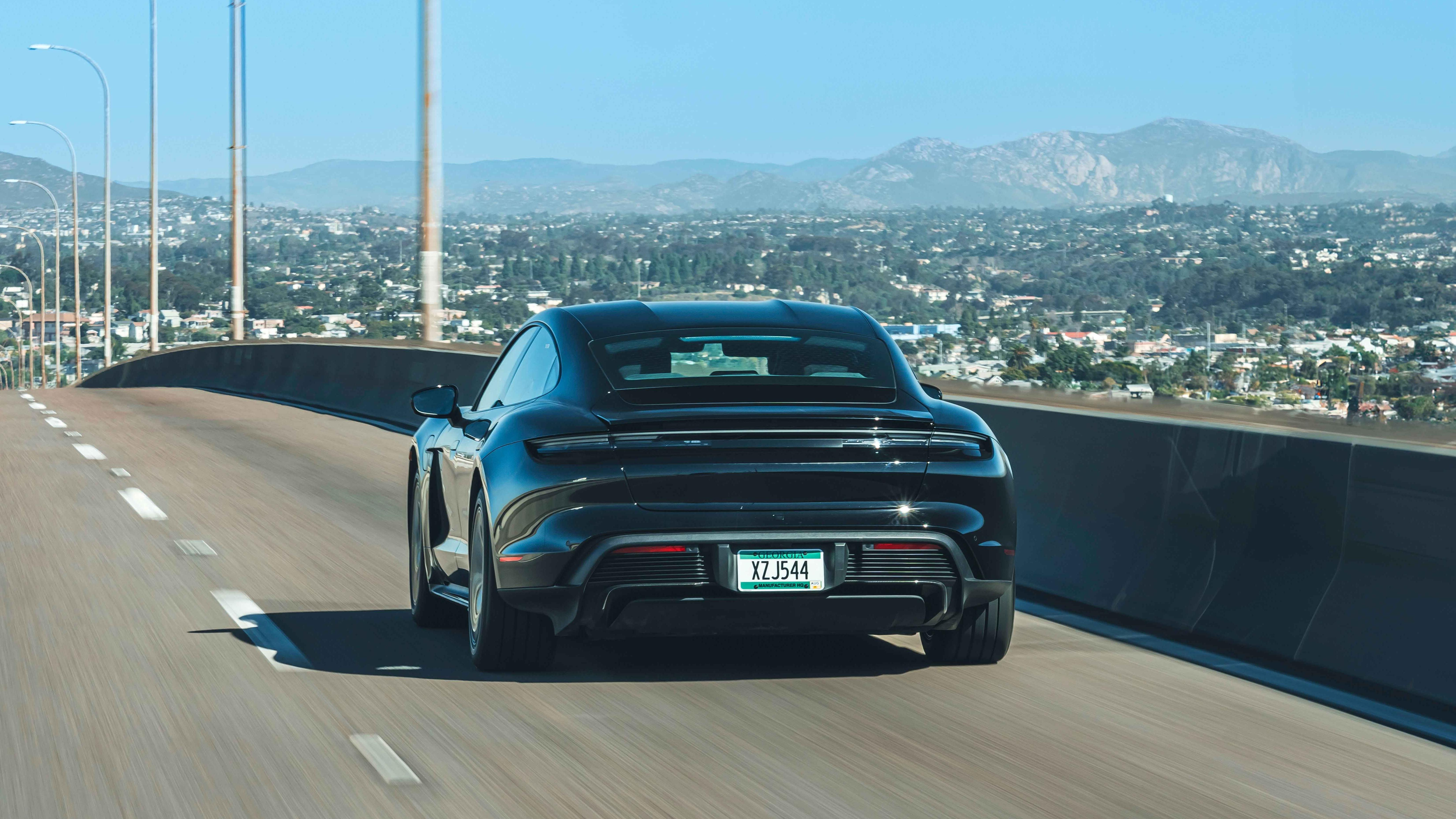 Rear view of a black 2025 Porsche Taycan sedan driving on the highway