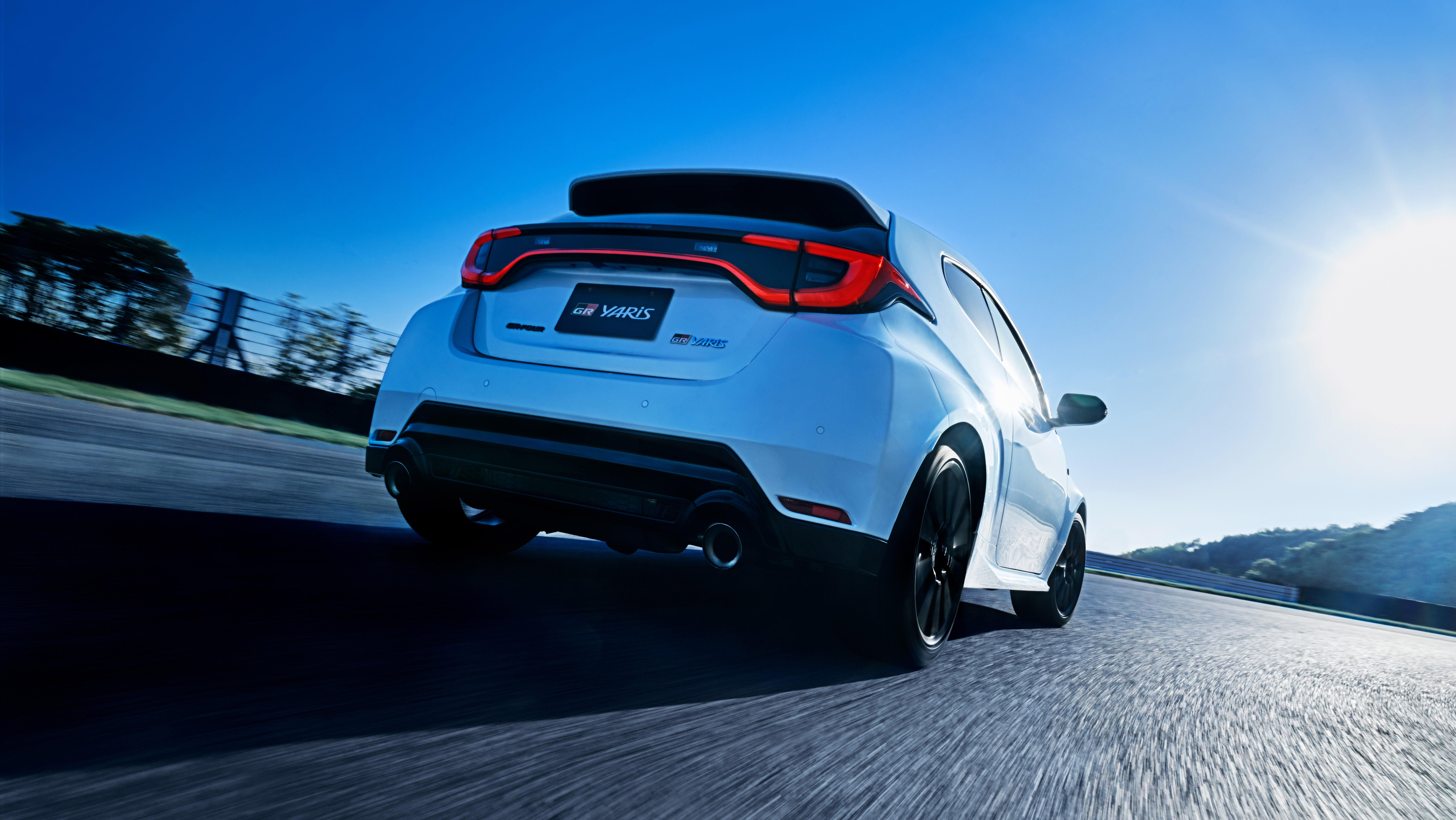 Rear 3/4 view of a white Toyota GR Yaris driving on track