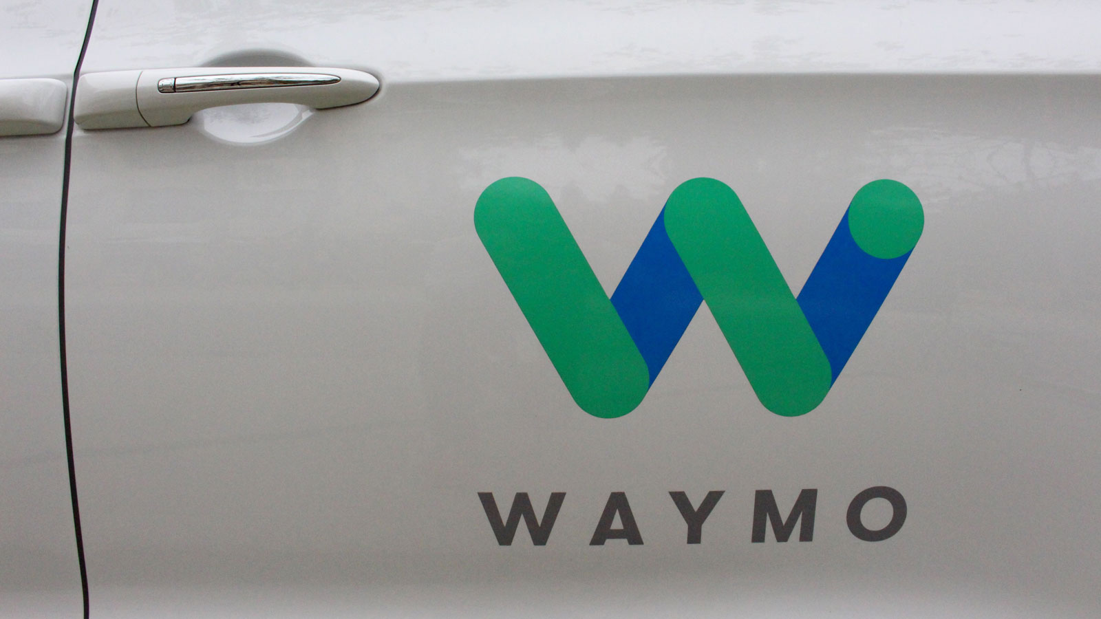 A photo of a Waymo logo on a car door. 