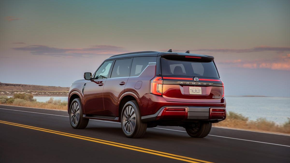 The rear of a red Nissan Armada Platinum Reserve driving near a body of water