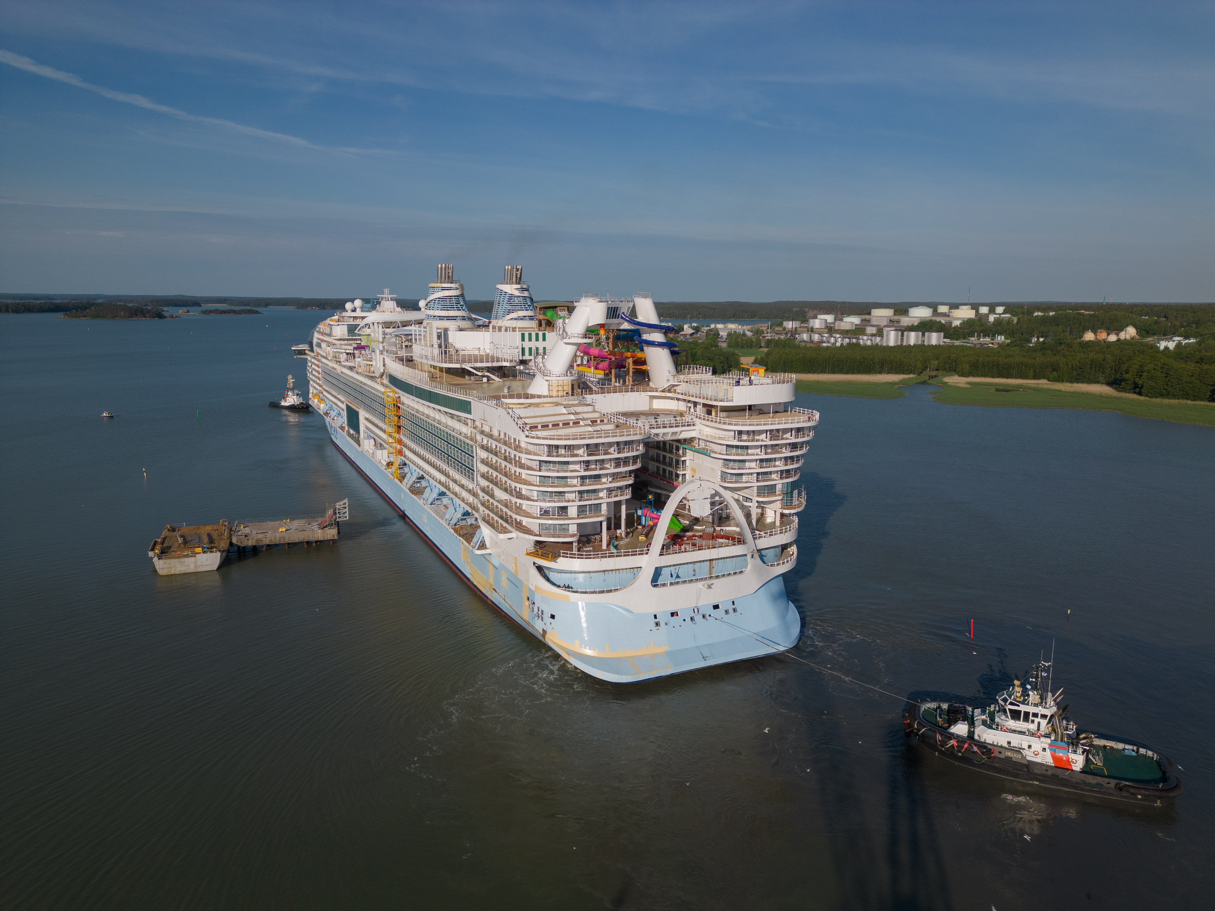 Icon of the Seas being escorted by tug boats