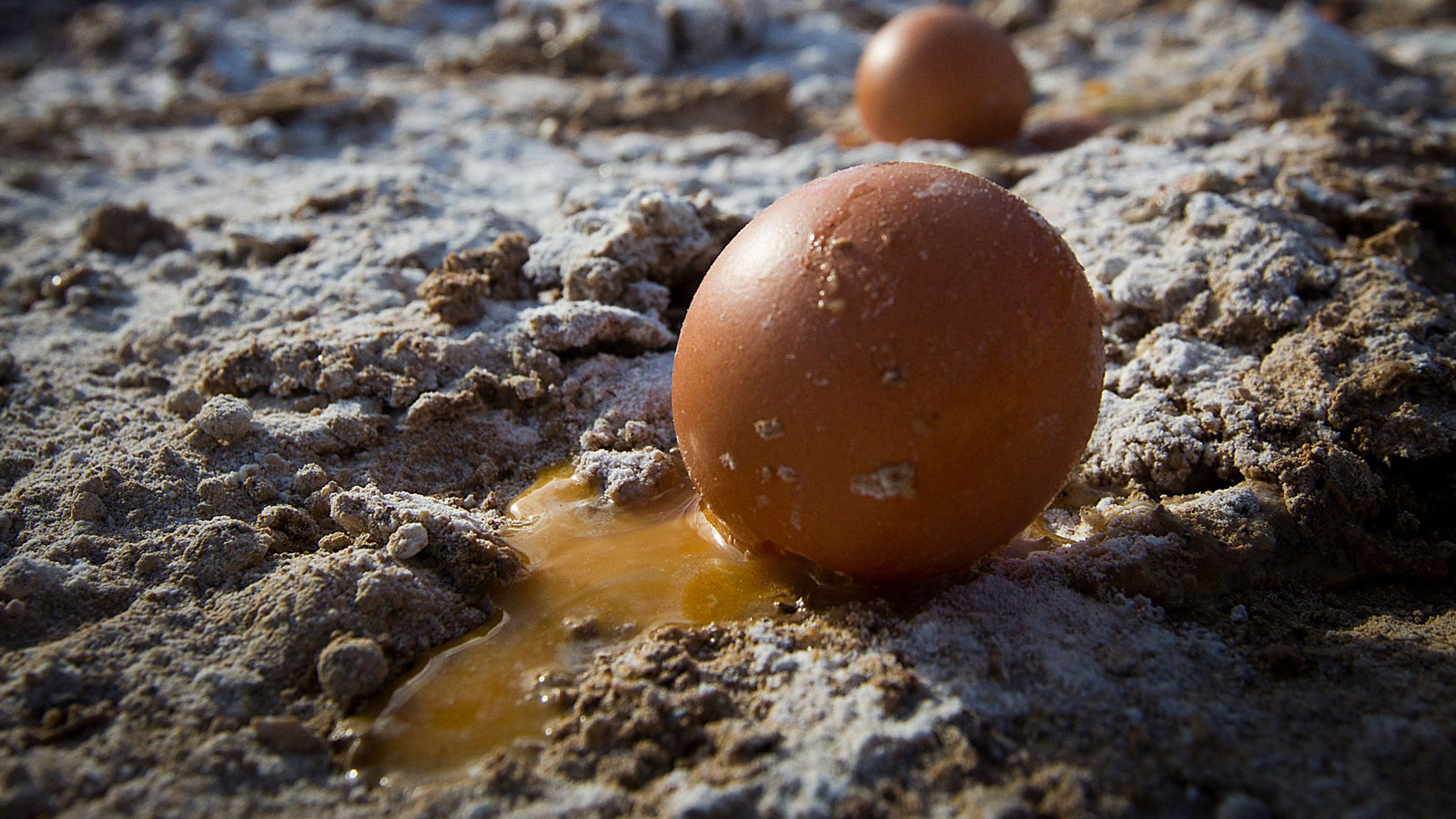 A photo of a cracked egg on the floor. 