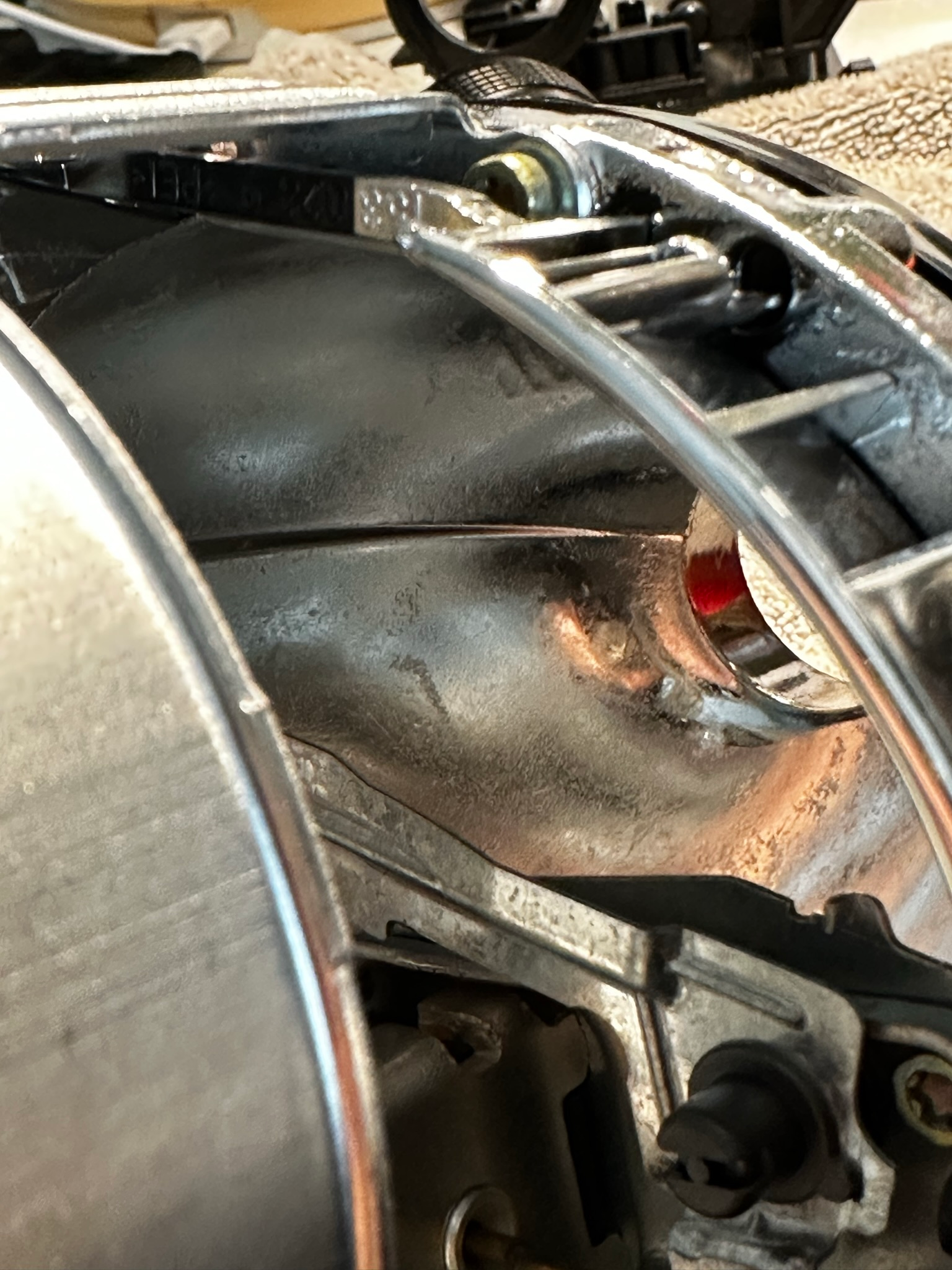 A worn out, pitted headlight projector reflector shown in close-up