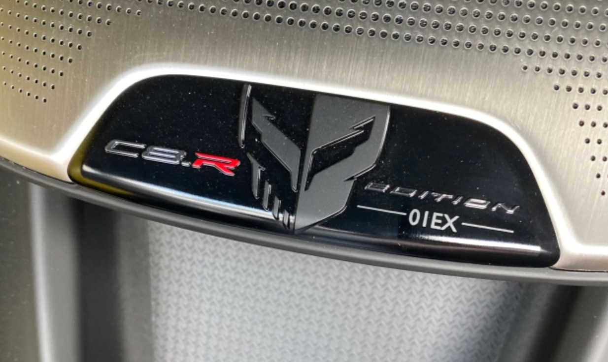 Close-up photo of a commemorative plaque on the dashboard of a 2021 Chevy Corvette. The plaque reads 