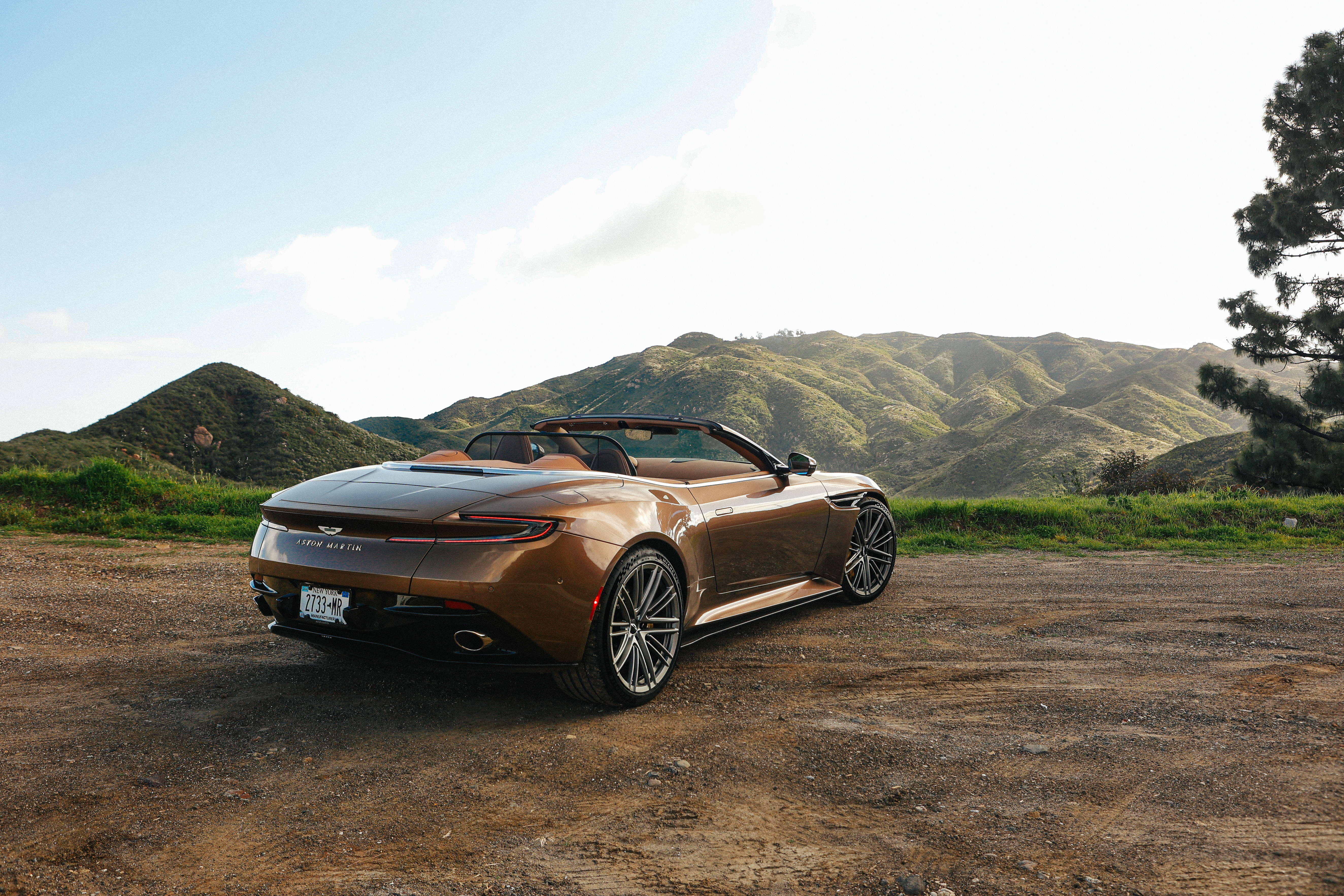 Rear 3/4 view of a brown Aston Martin DB12 Volante