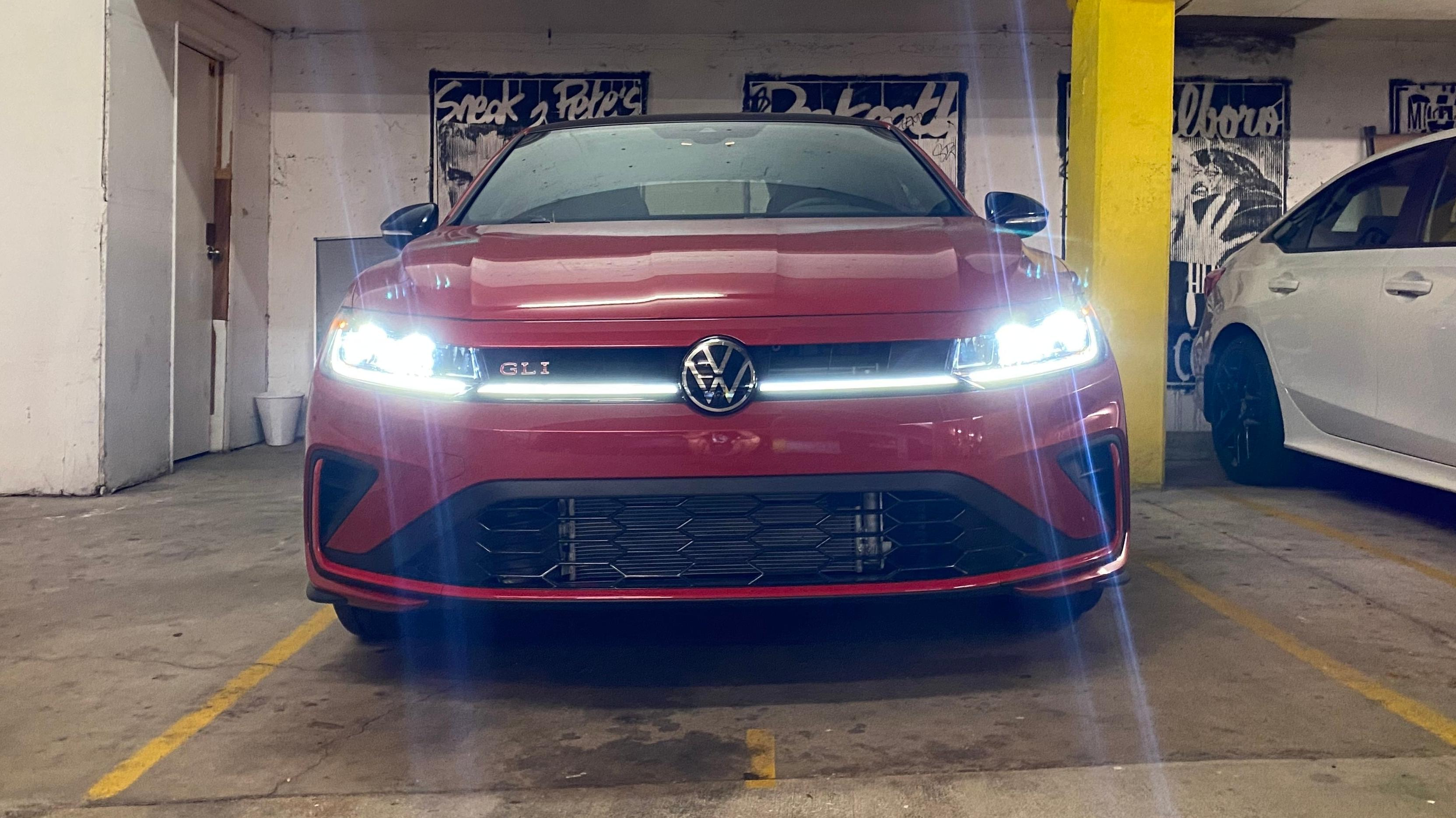 A shot of the front of the GLI in a garage with its lights on showing the light strip that runs the width of the front