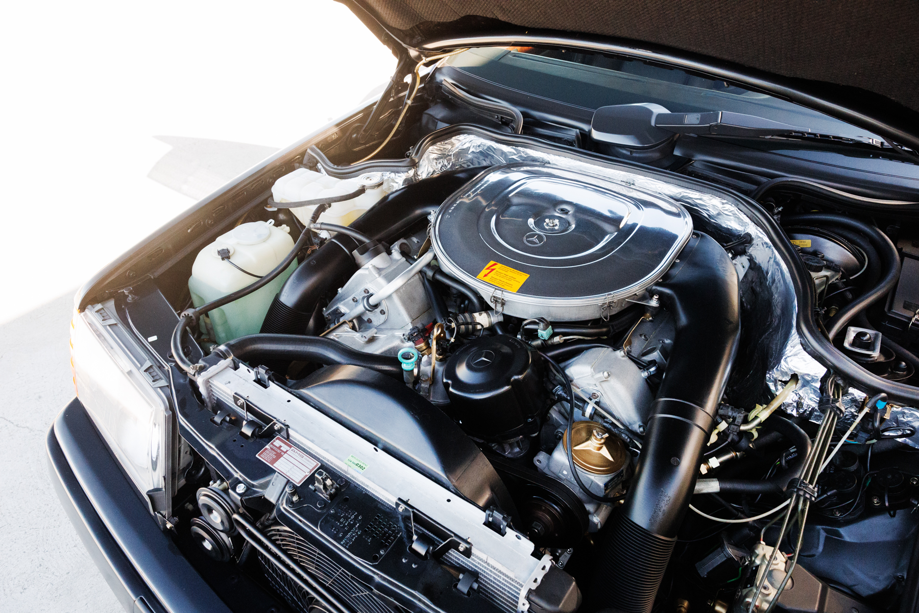 Engine bay of a black Mercedes-Benz AMG 300E 6.0 Hammer