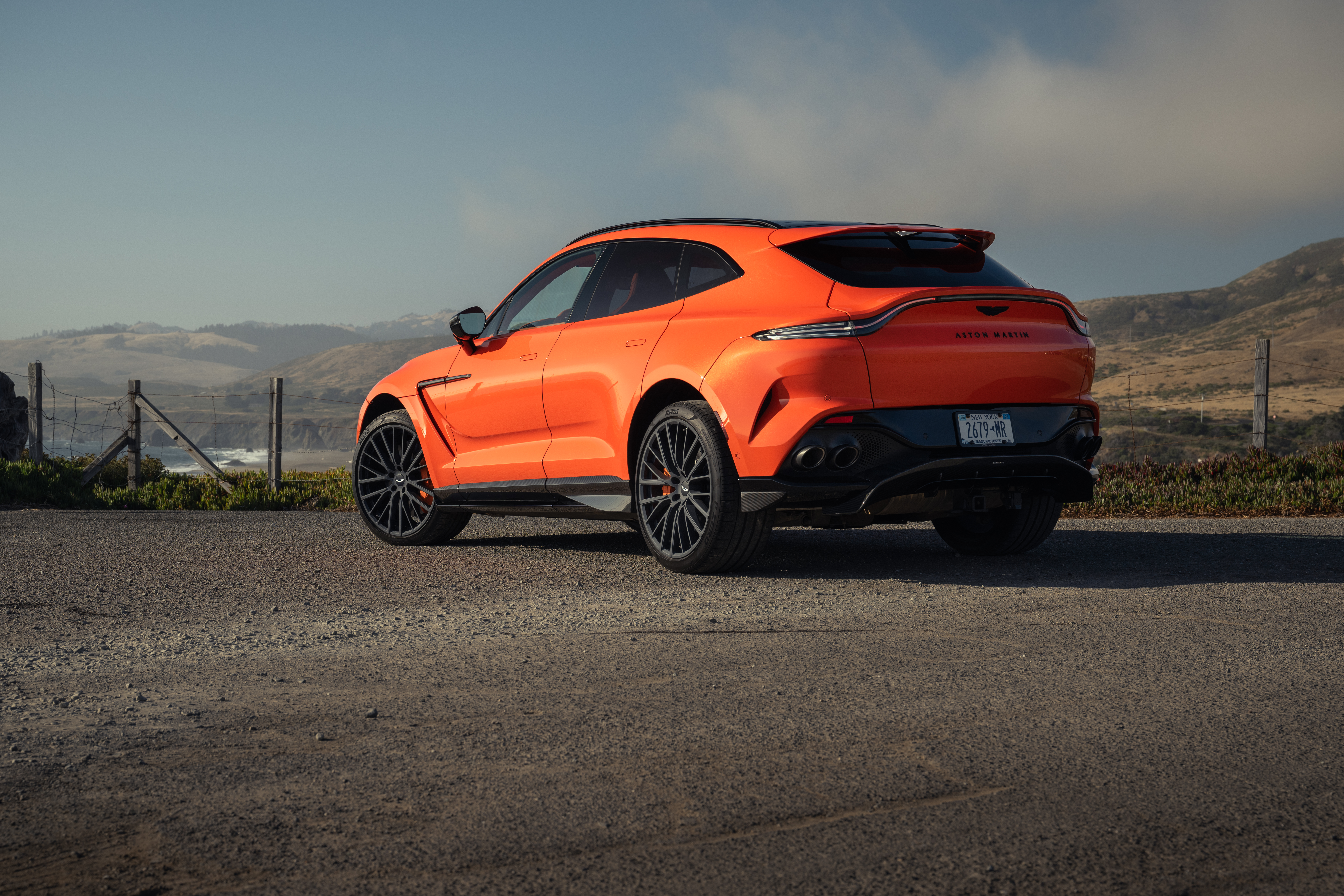 Rear 3/4 view of an orange 2025 Aston Martin DBX707