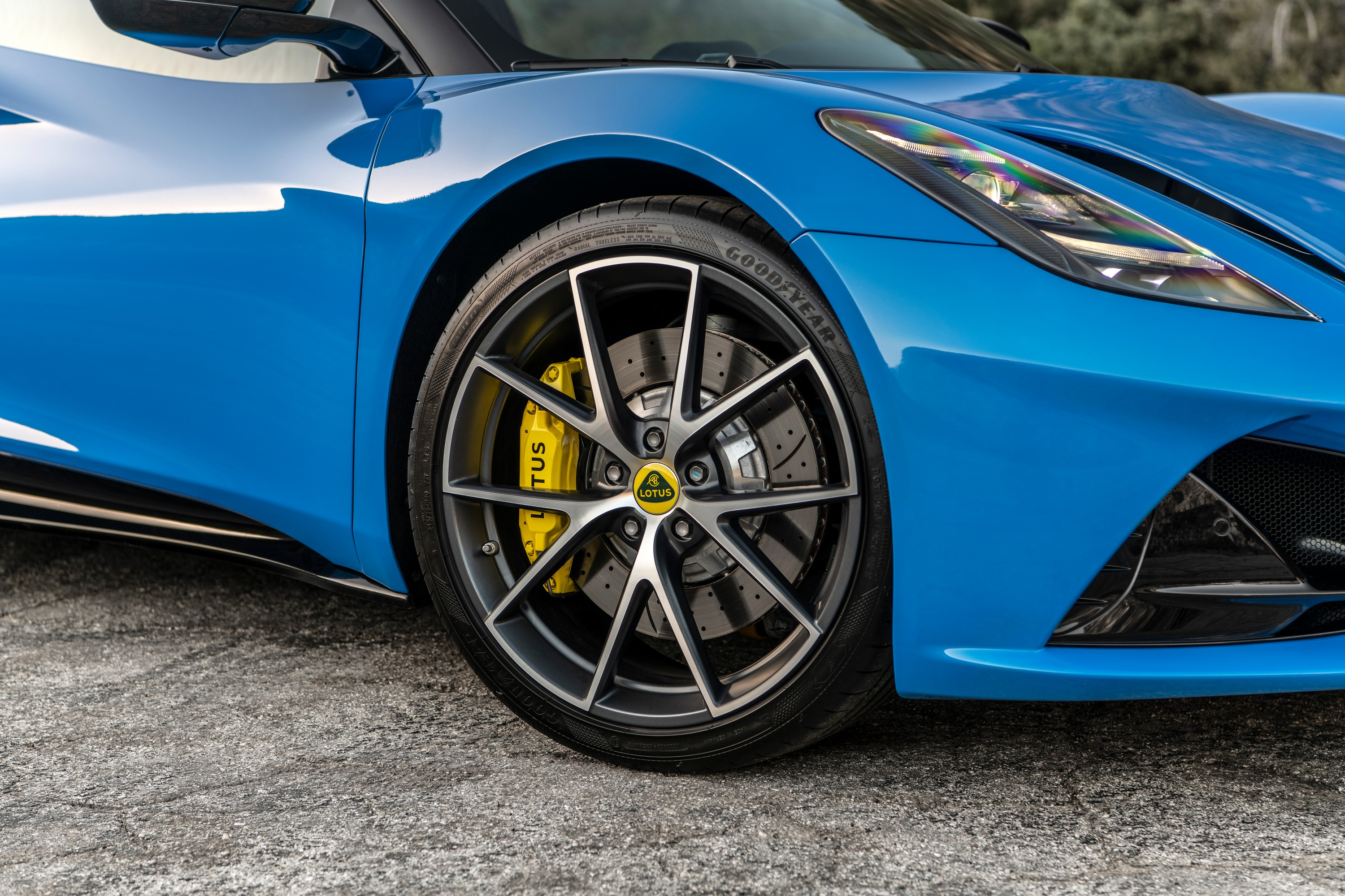 The right front wheel of a Seneca Blue 2023 Lotus Emira. The brake caliper is yellow.