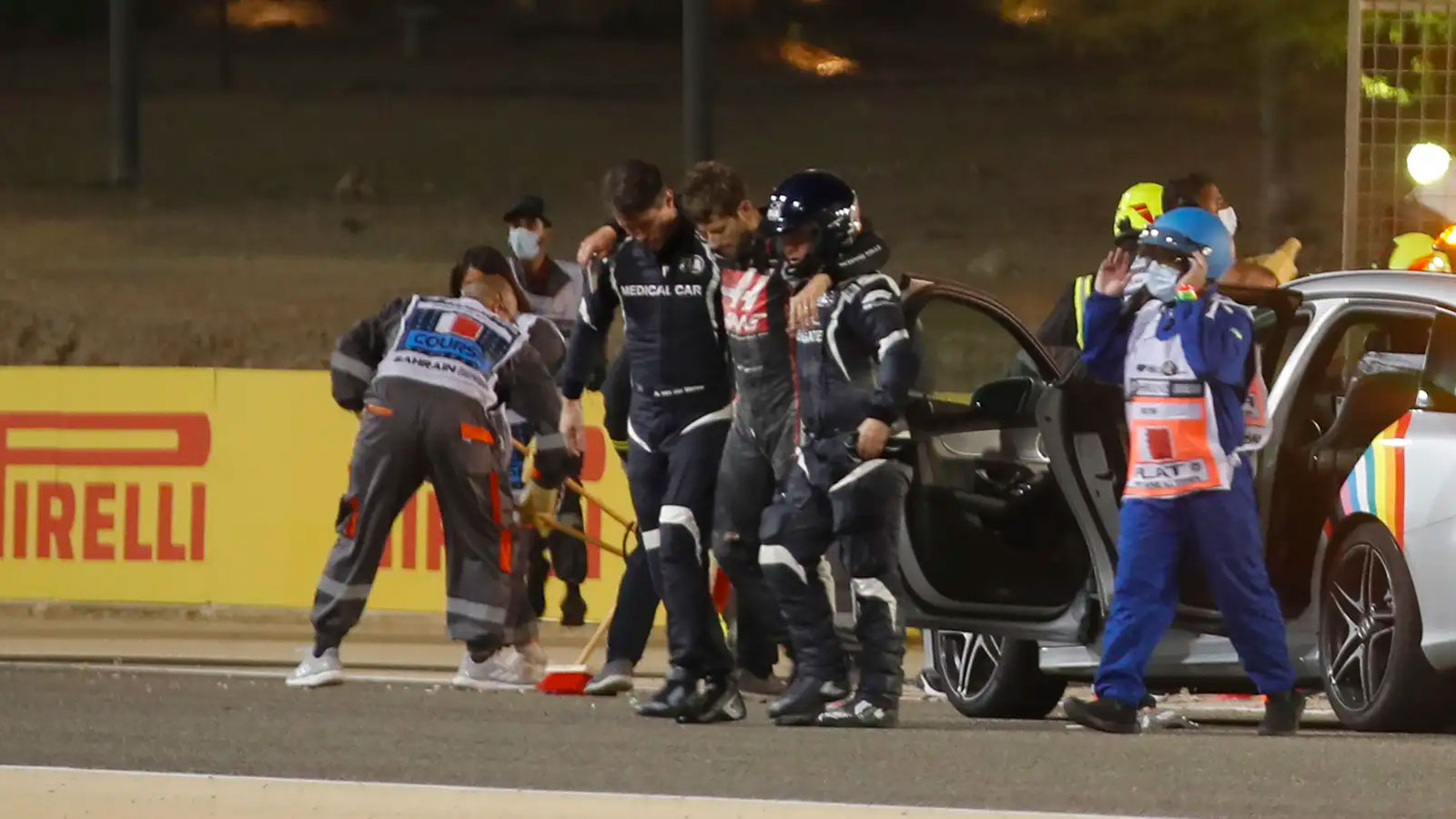 Romain Grosjean is lead away from a crash by the F1 medical team