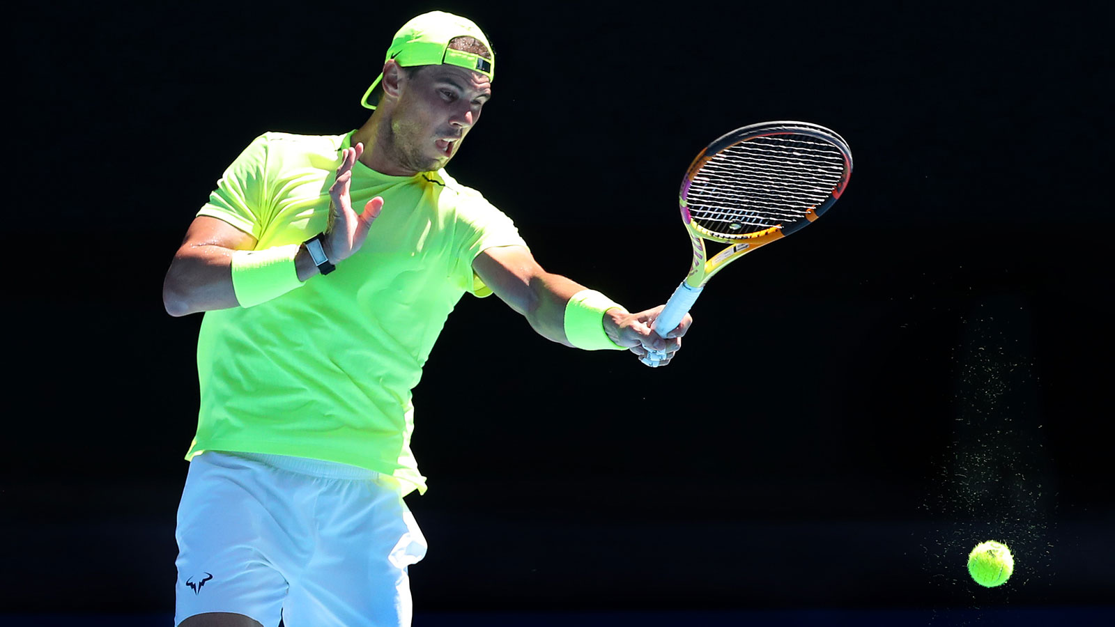 A photo of tennis player Rafael Nadal hitting a ball on a court. 