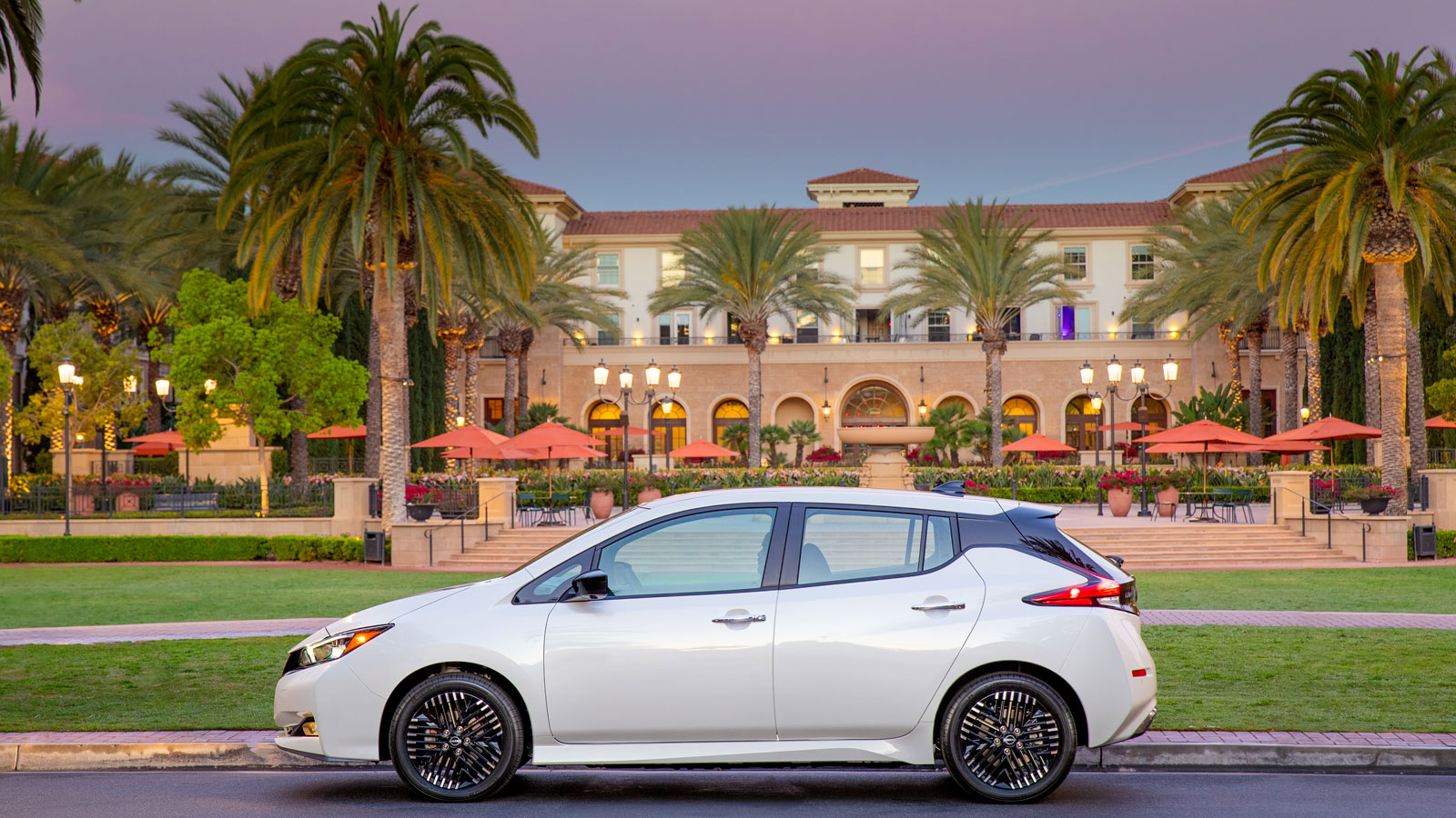 A side profile photo of a white Nissan Leaf EV with black wheels. 