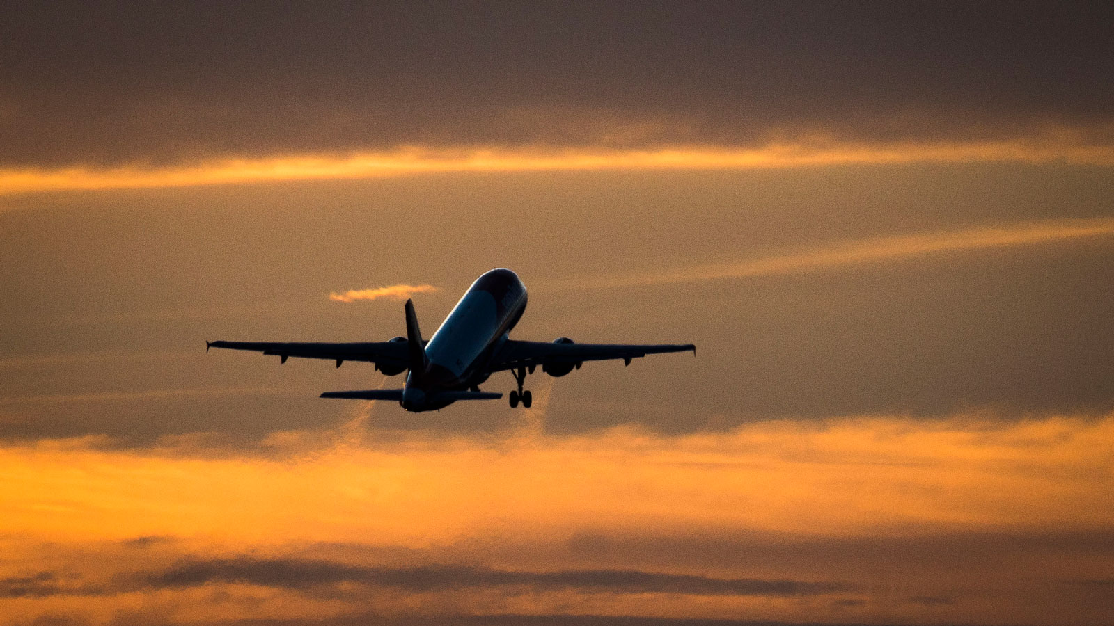 A photo of a plane taking off at sunset. 