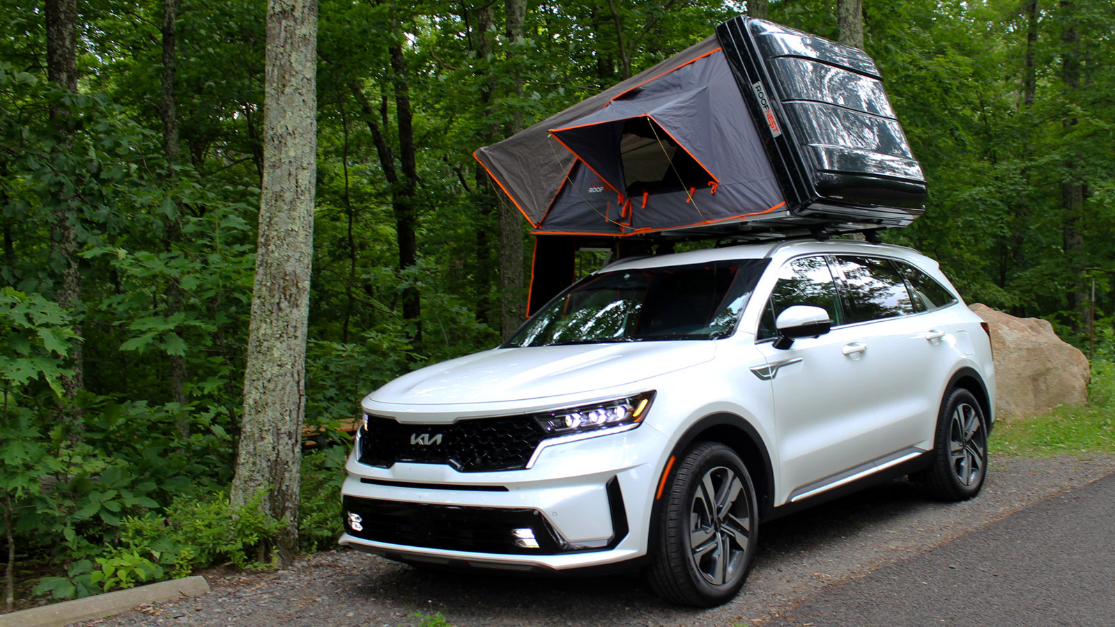 A photo of a set up Roofnest Condor tent on the top of a white Kia SUV. 