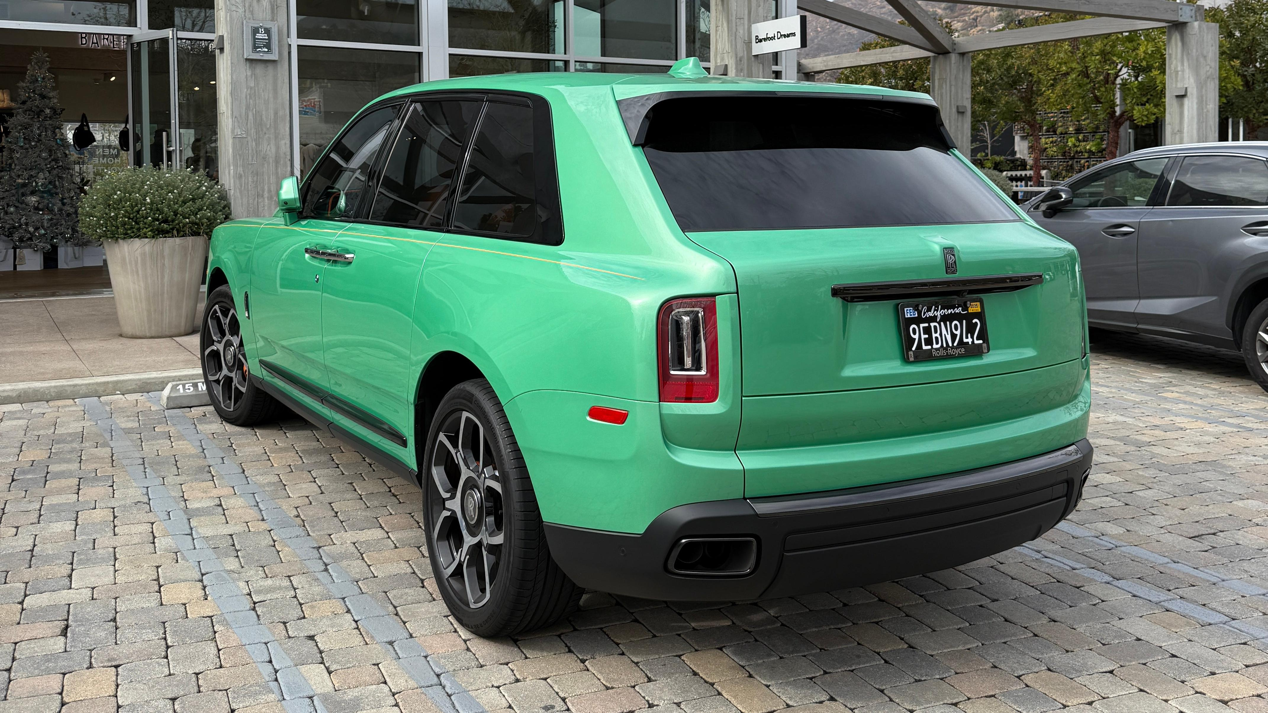 Rear 3/4 view of a green Rolls-Royce Cullinan Black Badge