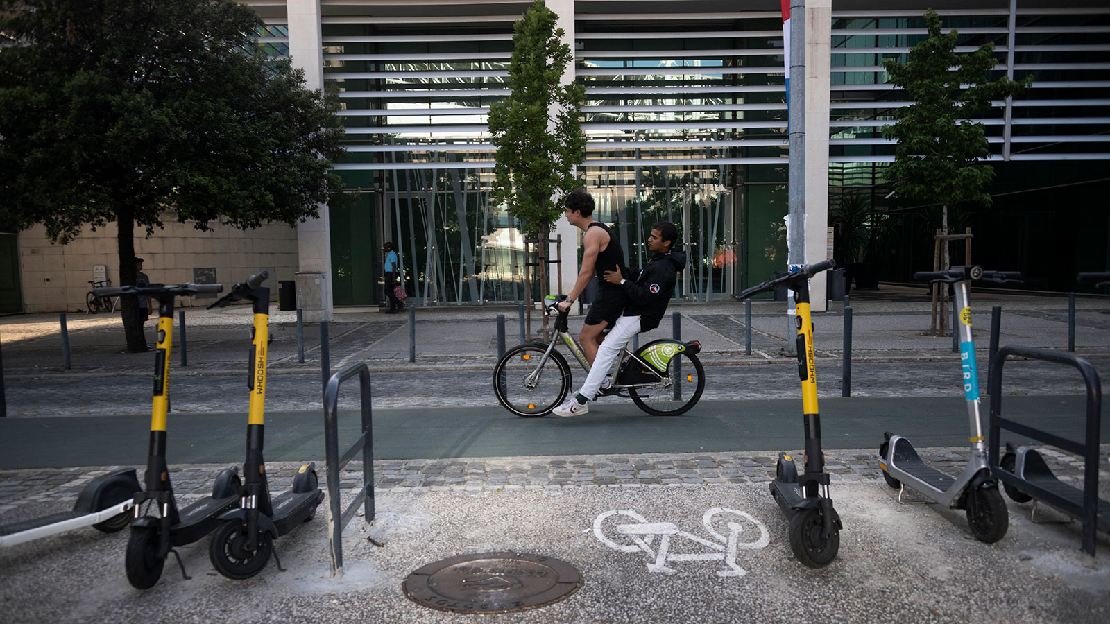 A photo of a bike riding past a row of electric scooters. 