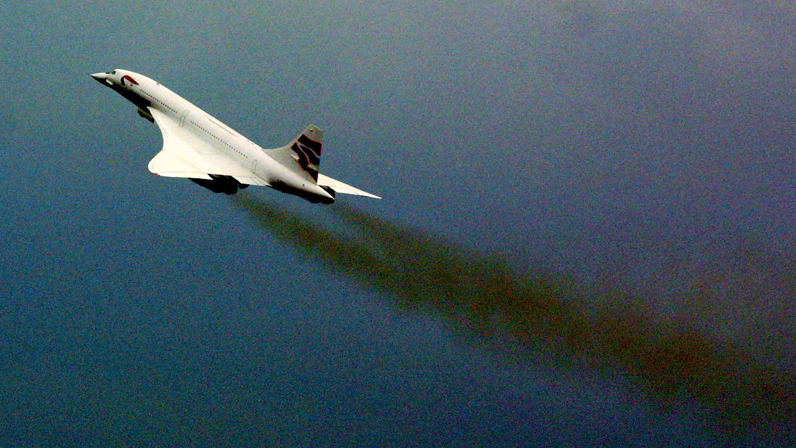 A photo showing streams of black smoke coming from the engines of a Concorde plane. 