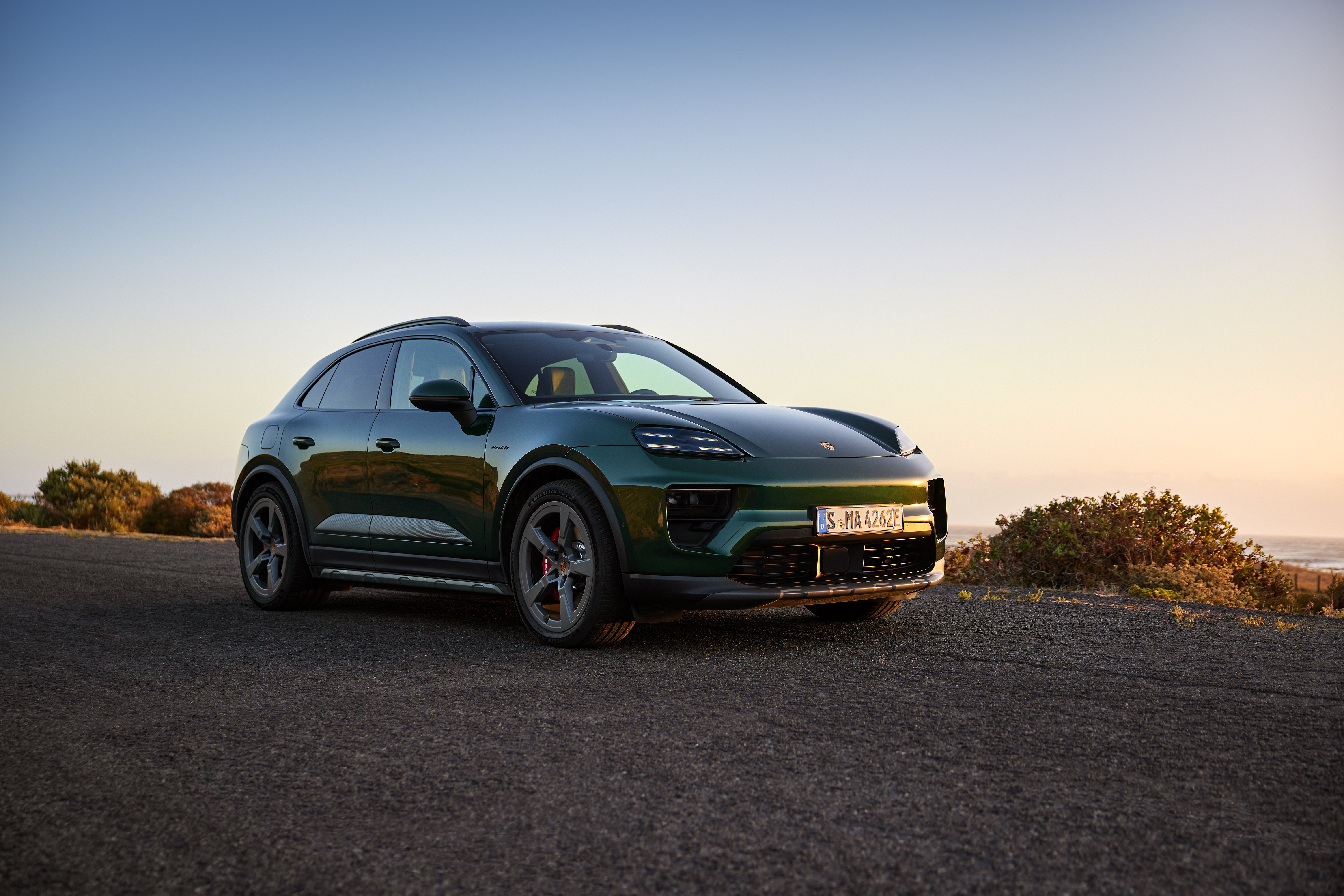 Front 3/4 view of a green Porsche Macan 4S EV