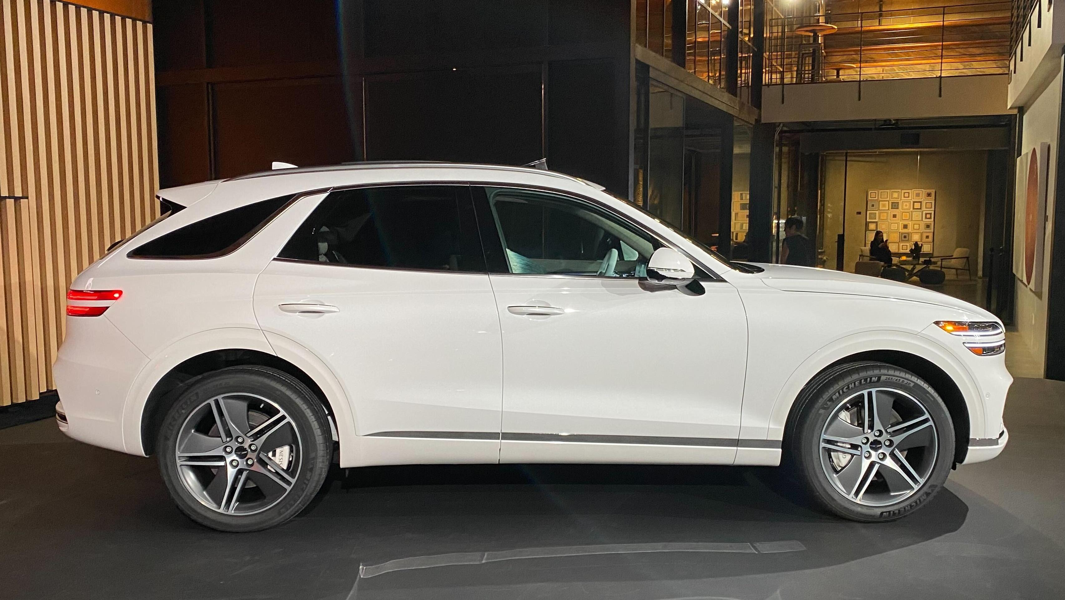 A side view of a white GV70 Electrified parked on a stage