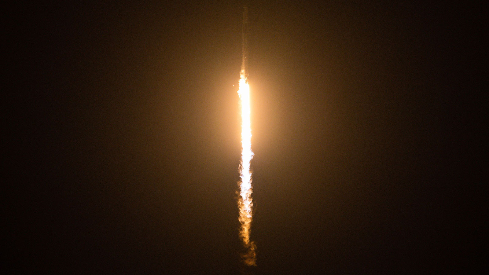 A photo of a space rocket launching at night. 