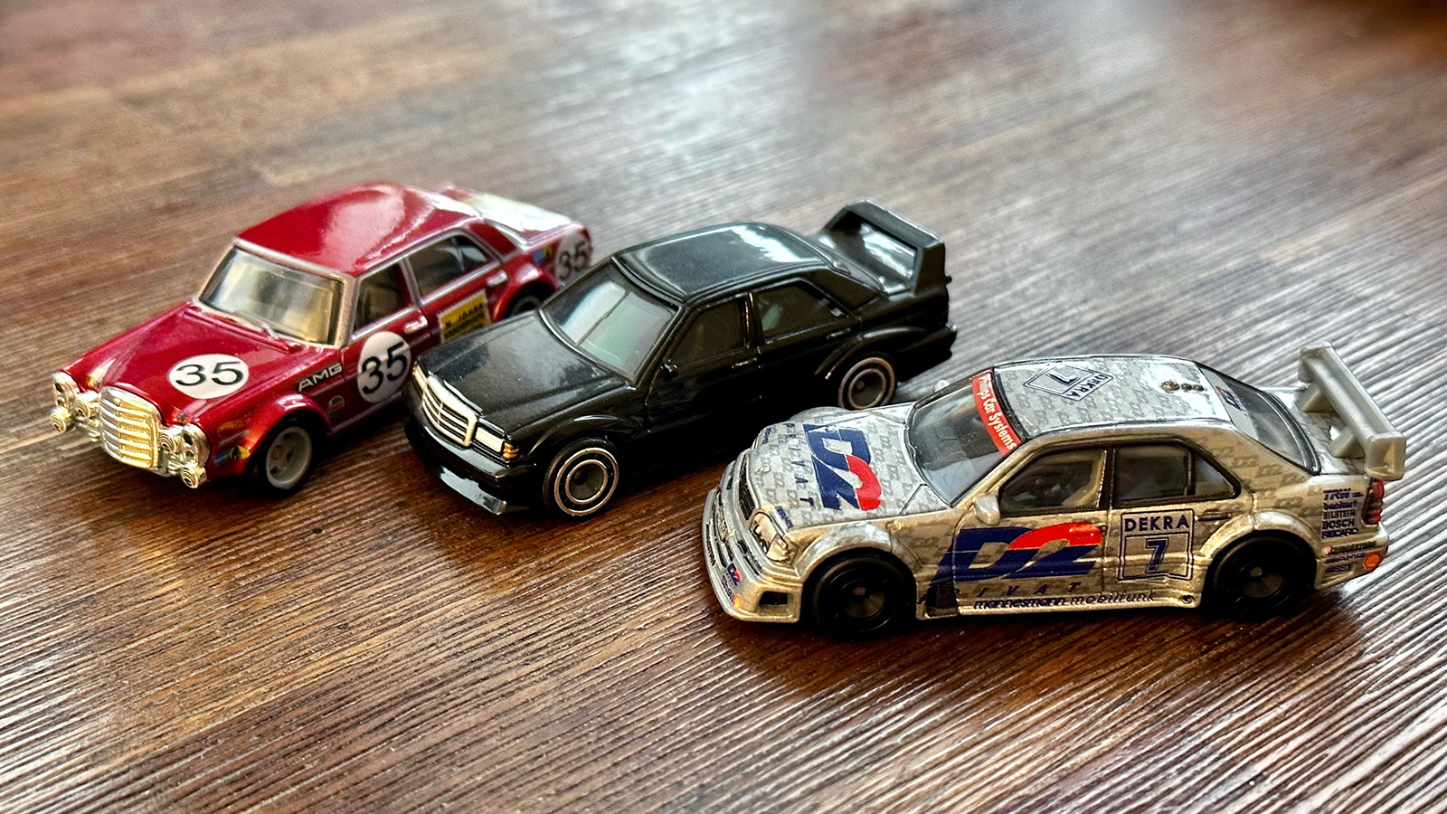 A photo of Hot Wheels diecasts. From left to right: Mercedes-Benz 300 SEL 6.8 AMG, 190E 2.5-16 Evolution II and W202 C-Class DTM.