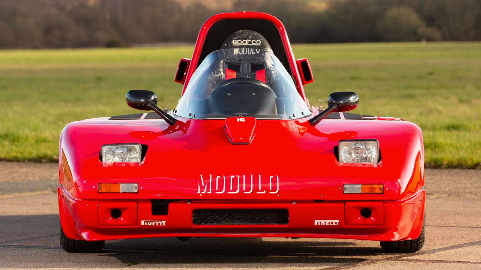 A photo of the front of a red Modulo three-wheeled car. 