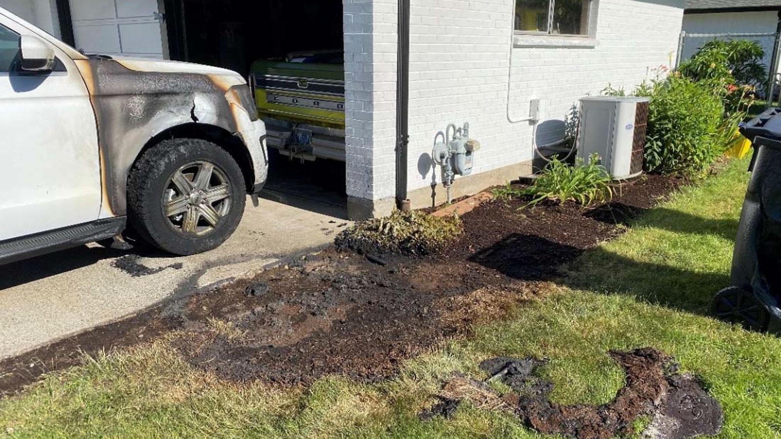 A photo of a burned Ford Explorer SUV and singed grass around it. 