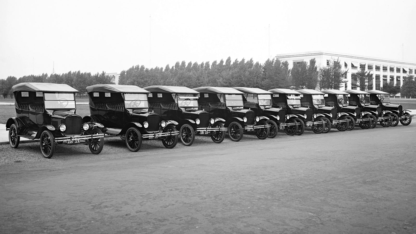 A black and white photo of a line of Model T Ford cars 