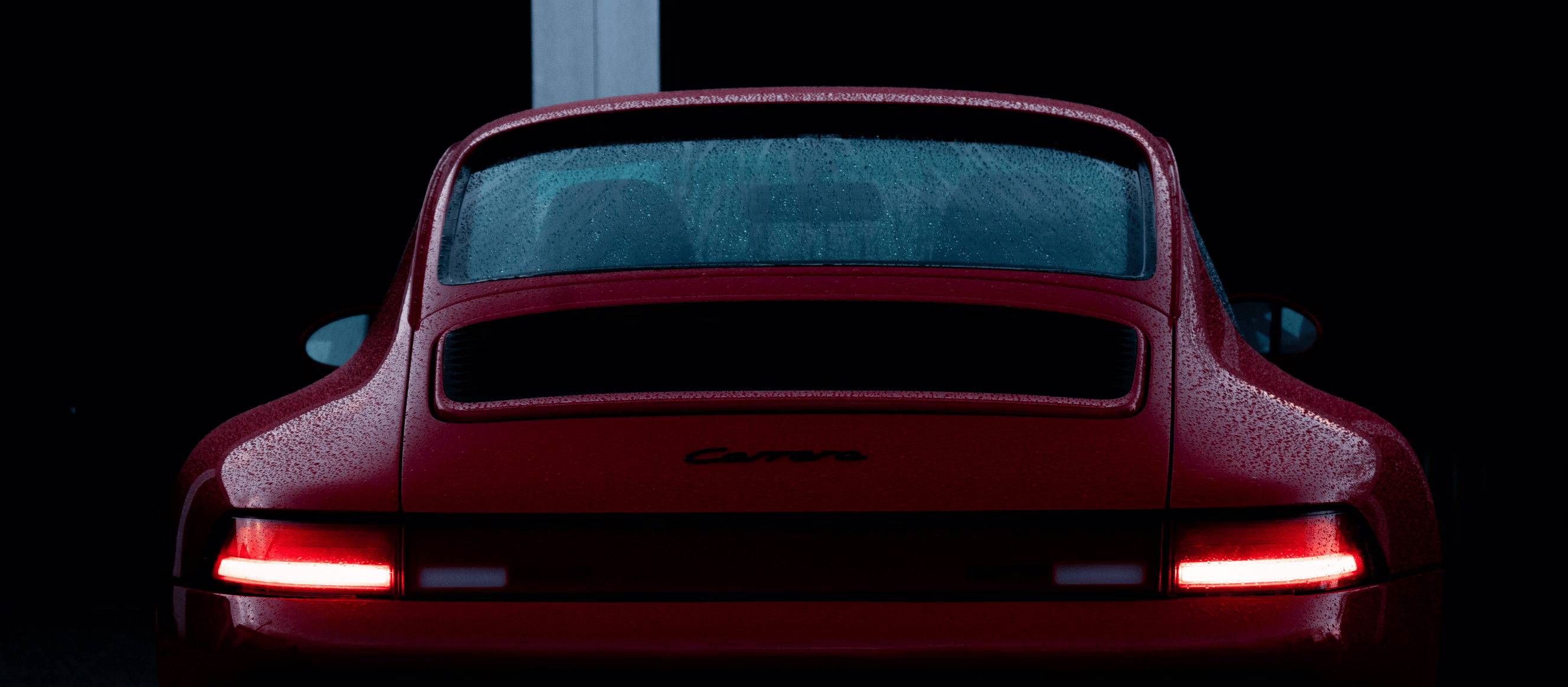 a photo of the rear of a wet red 993 with the LED tail lights iluminated 