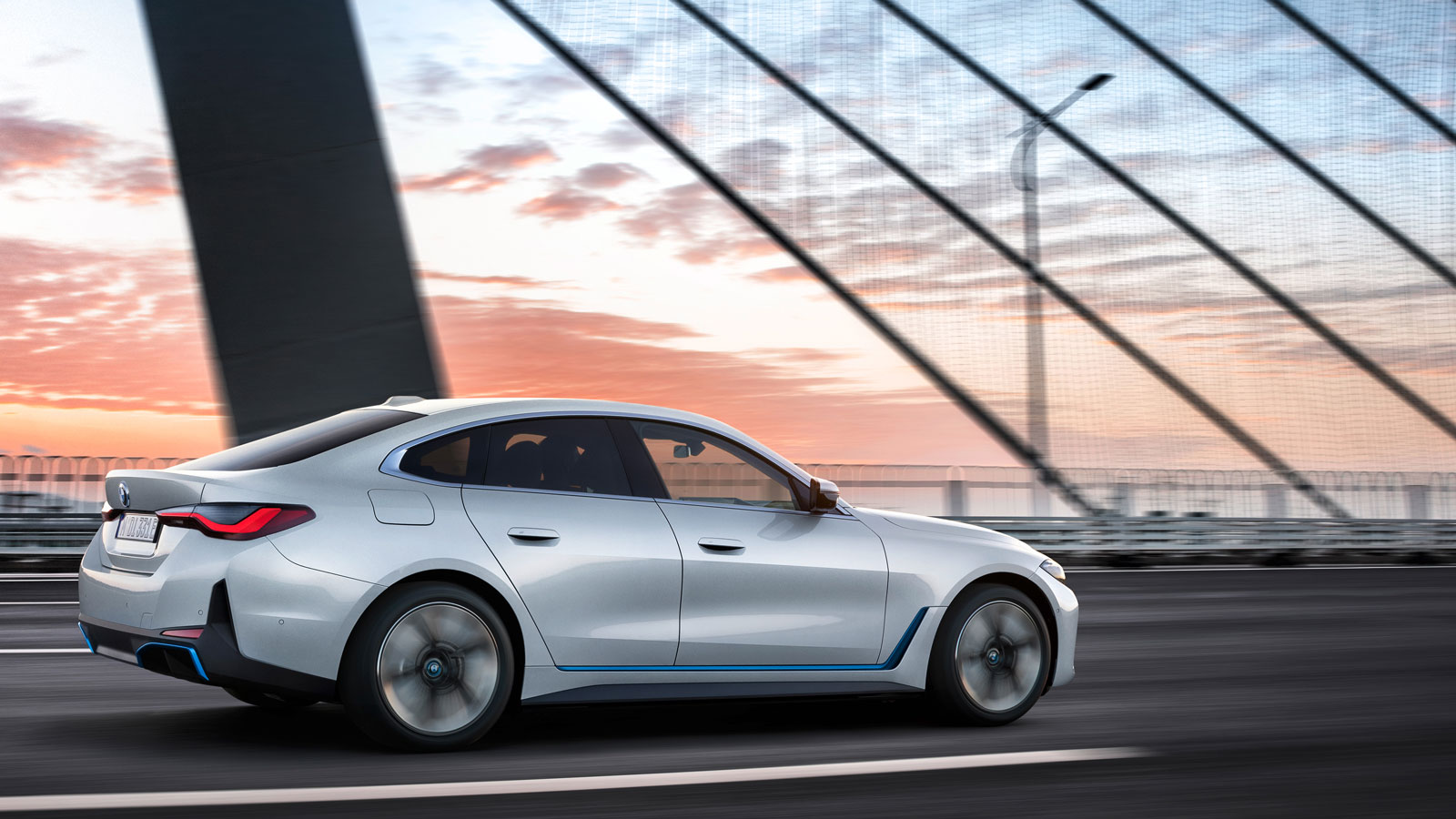 A photo of a white BMW i4 driving across a bridge.